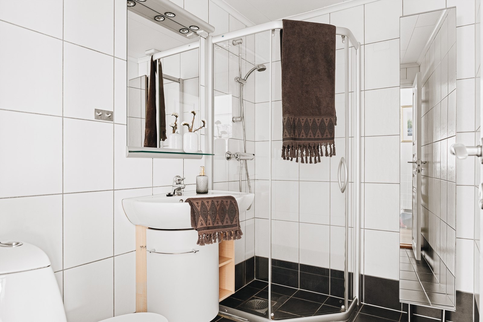 Badet er pent innredet med toalett, dusjhjørne, servant med møblement og speil/belysning Galleribilde
