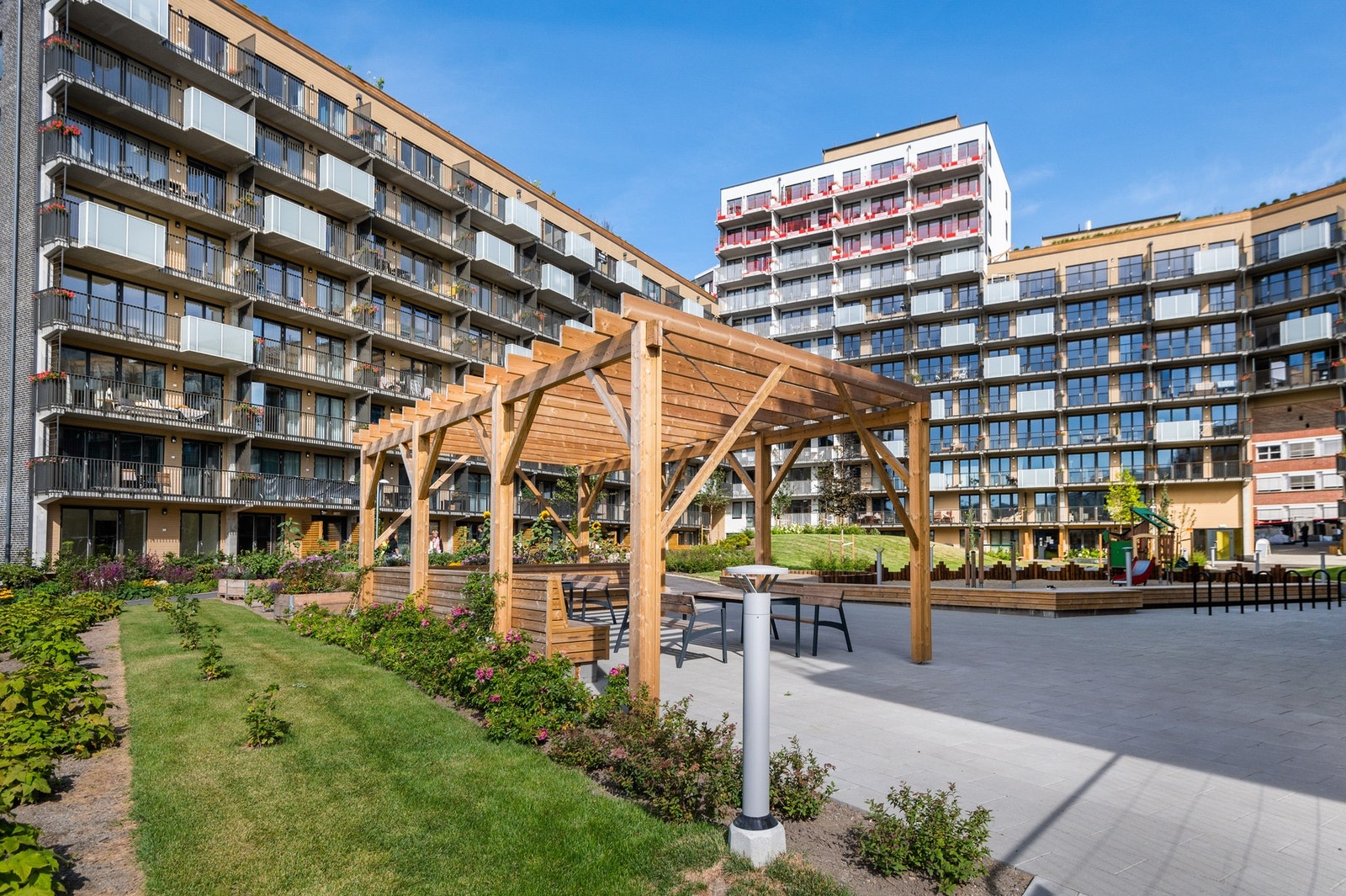 Fellesområdet er pent opparbeidet med pergolaer, asfalterte veier, gressplen og lekeplass. Galleribilde