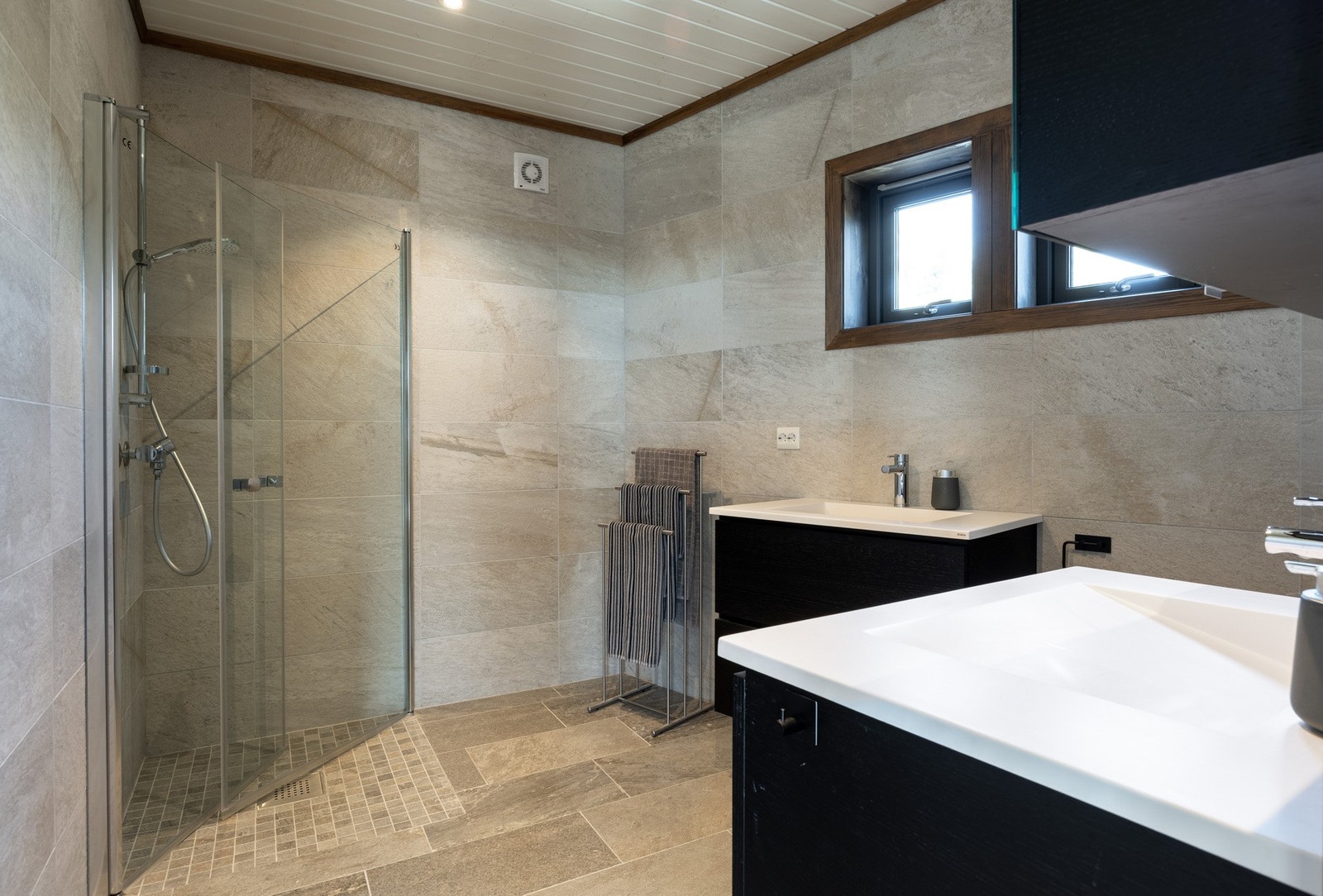 Romslig helfliset baderom med 2 design servanter. Innredning fra Kvik i samme stil som kjøkkenet. Tre baderoms vinduer gir godt med lys. Galleribilde