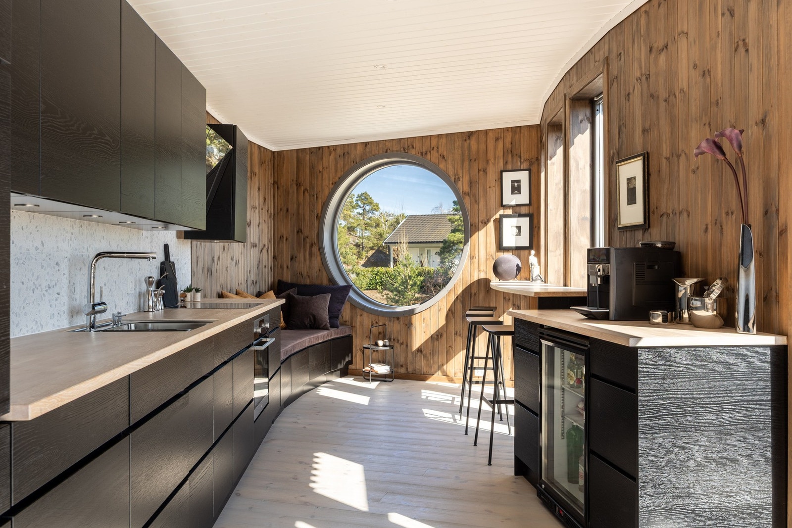 Vinklingen av veggen med det runde vinduet på kjøkkenet fanger opp morgensolen. Galleribilde