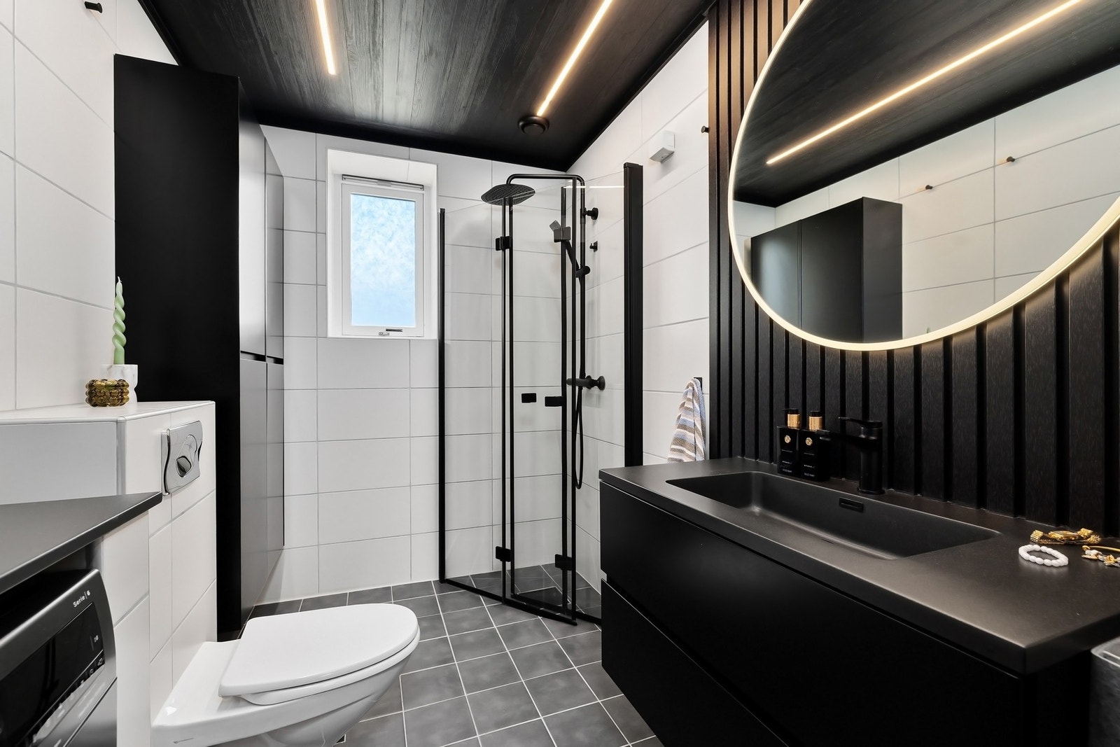 Badet har et moderne uttrykk og en tøff stil med god plass til toalettartikler Galleribilde