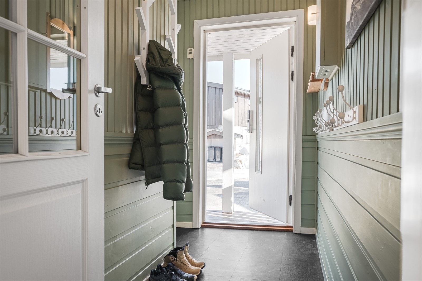 Lun og trivelig entré med vinylfliser på gulv og malte panelvegger. Her er det plass til gardeobemøbel og oppheng til ytterjakker. Fra entréen er det adkomst til gang med garderobe. Galleribilde