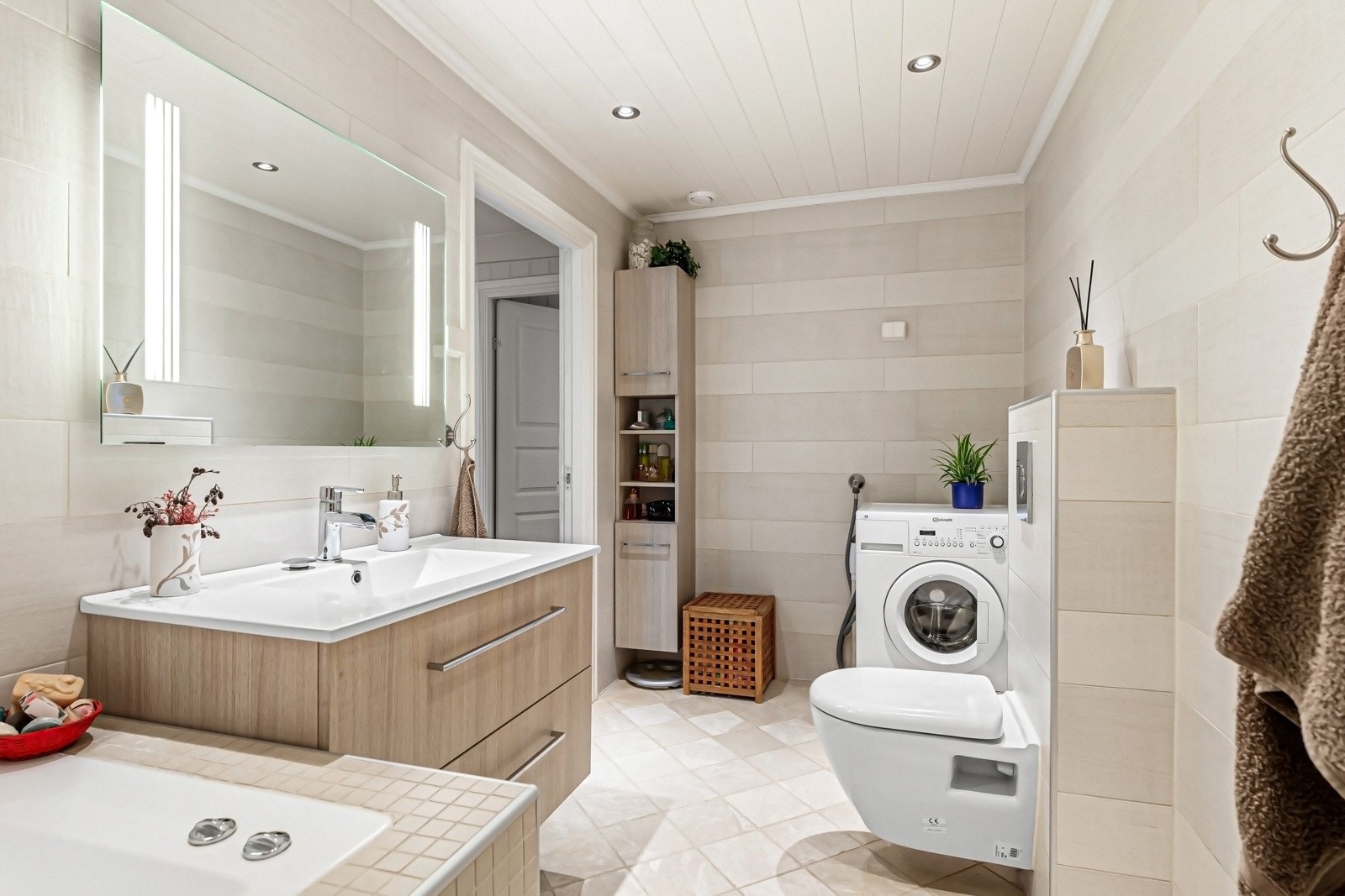 Badet har innredning med skuffer og servant med ettgreps kran og speil med integrert lys. Opplegg for vaskemaskin, innmurt boblebadekar og dusjnisje Galleribilde