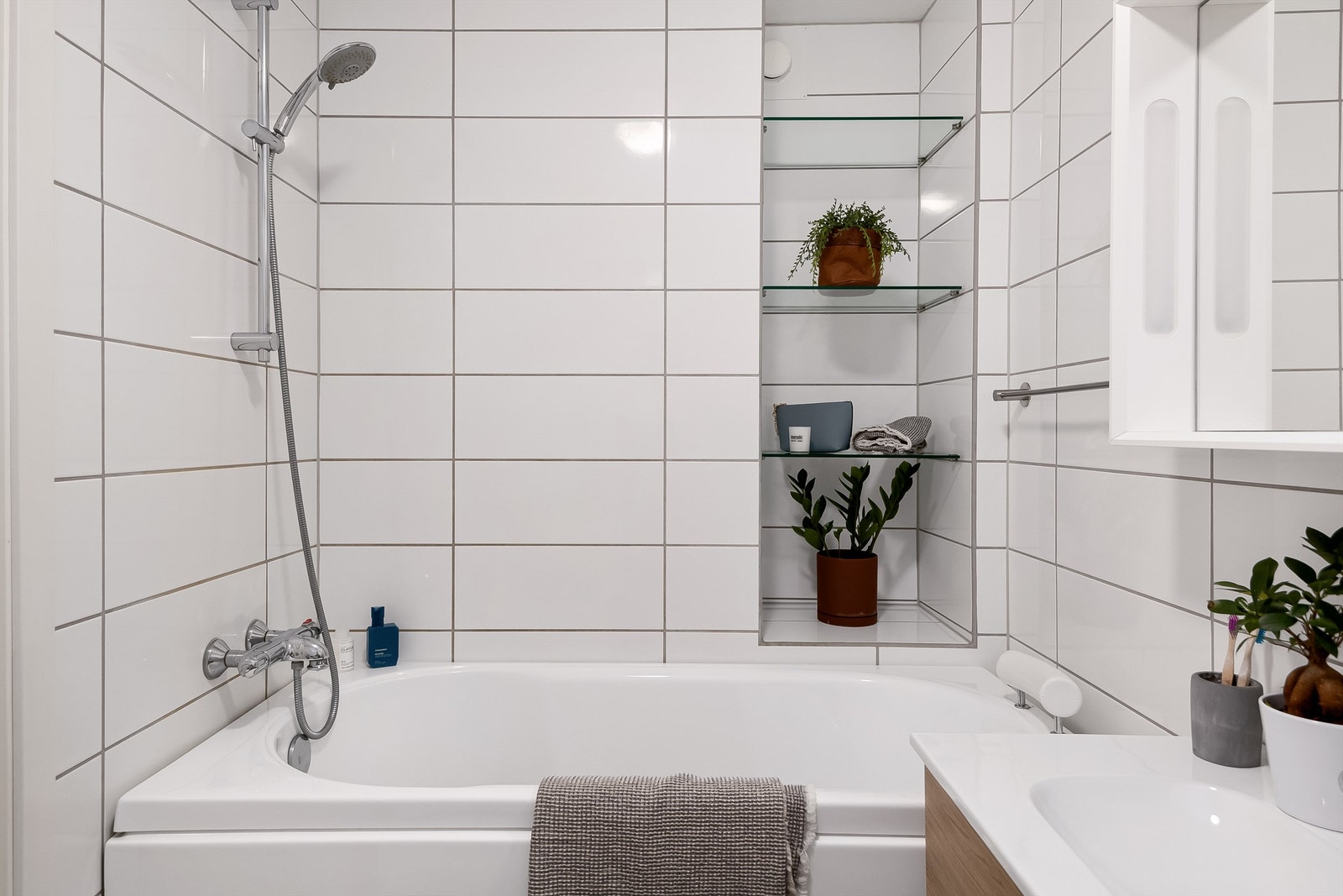 Videre er badet utstyrt med servantskap med overskap og speil med lys, vegghengt toalett og badekar med vegghengt badekararmatur. Galleribilde
