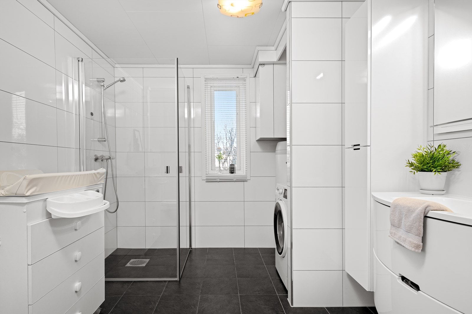 Badet er utstyrt med dusjnisje, servant i innredning, skap, vannuttak for vaskemaskin, vegg hengt toalett og bereder. Galleribilde