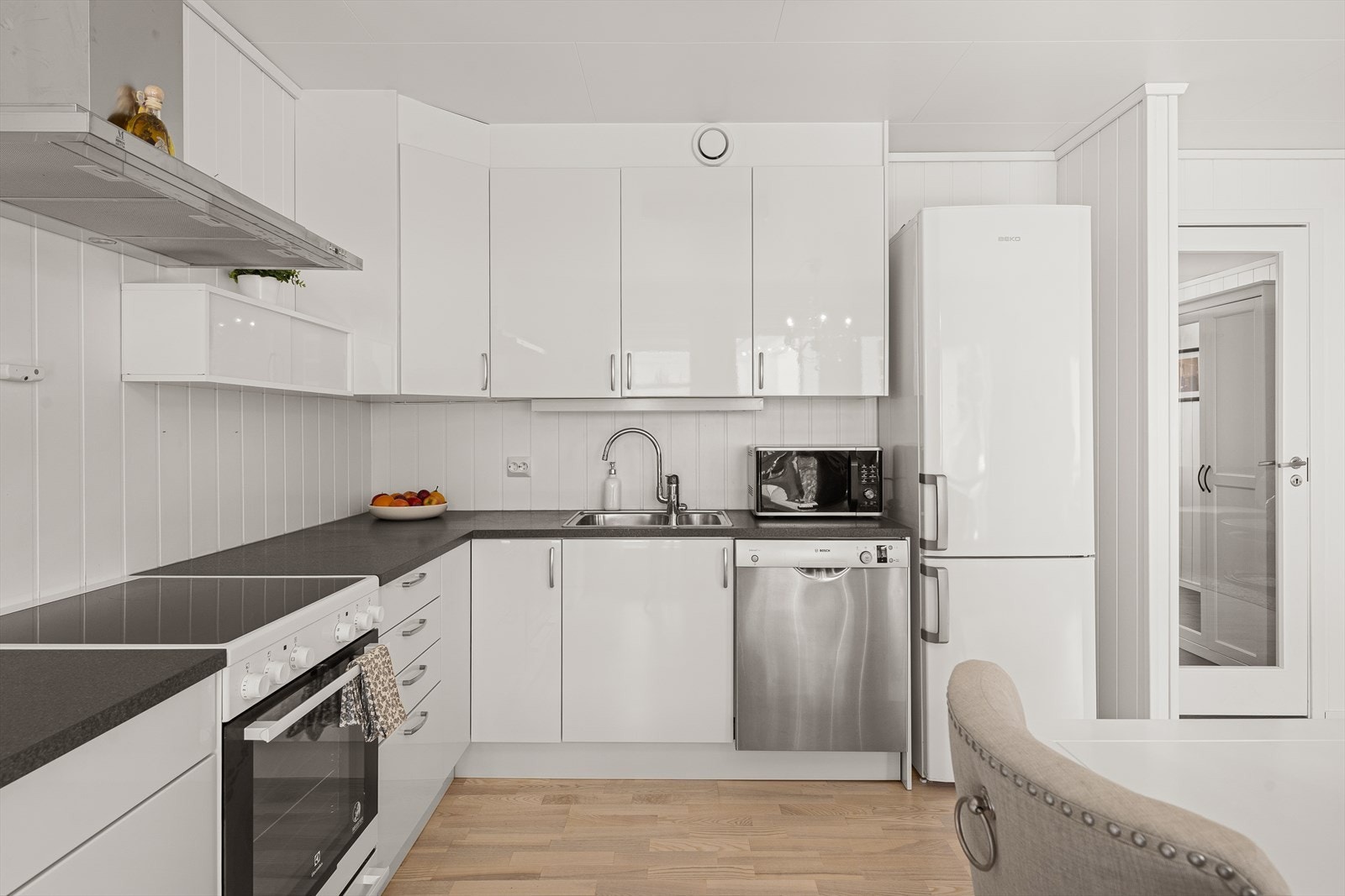 Kjøkkeninnredning med hvit slett fronter og grå laminert benkeplate. Her er det god skap- og skuffplass til oppbevaring. Galleribilde