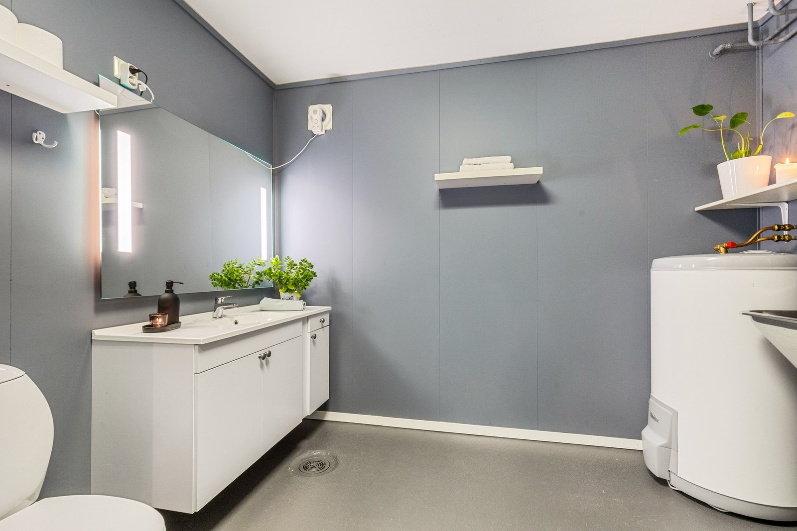 Praktisk vaskerom av god størrelse innredet med servant med underskap, toalett og utslagsvask Galleribilde