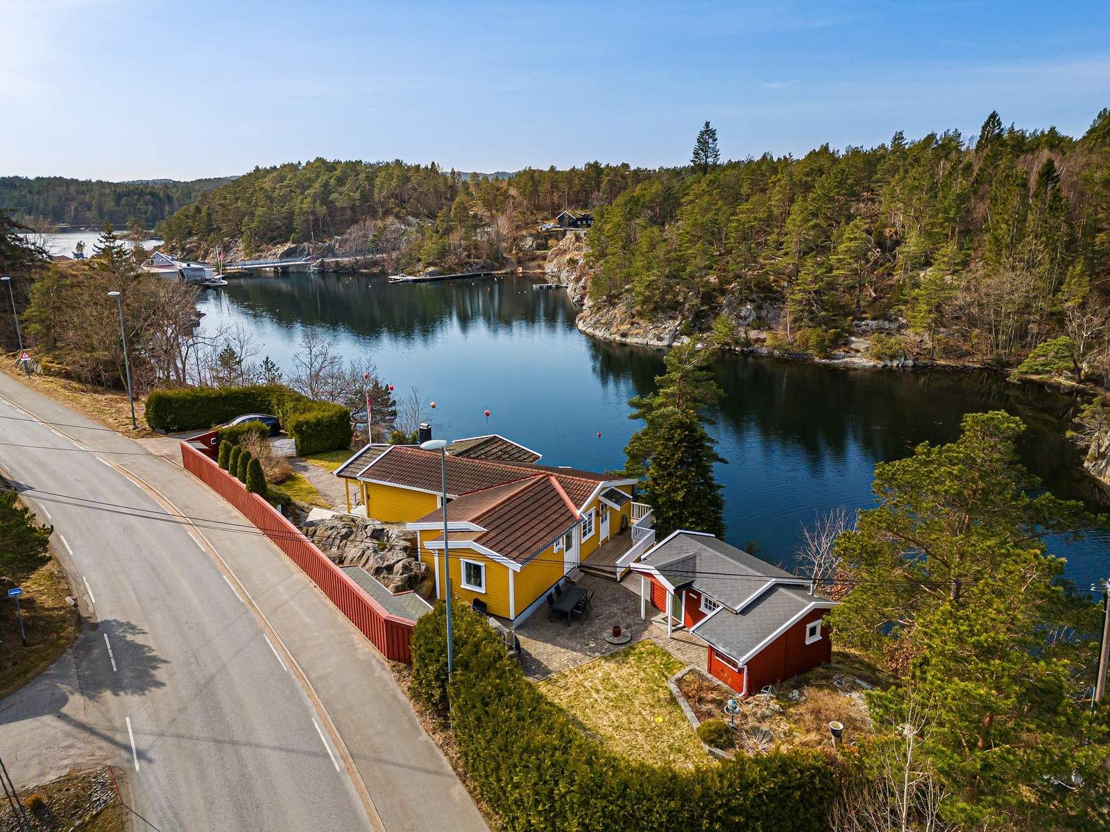Hytten ses midt i bilde - på baksiden av hekk ved veien Galleribilde