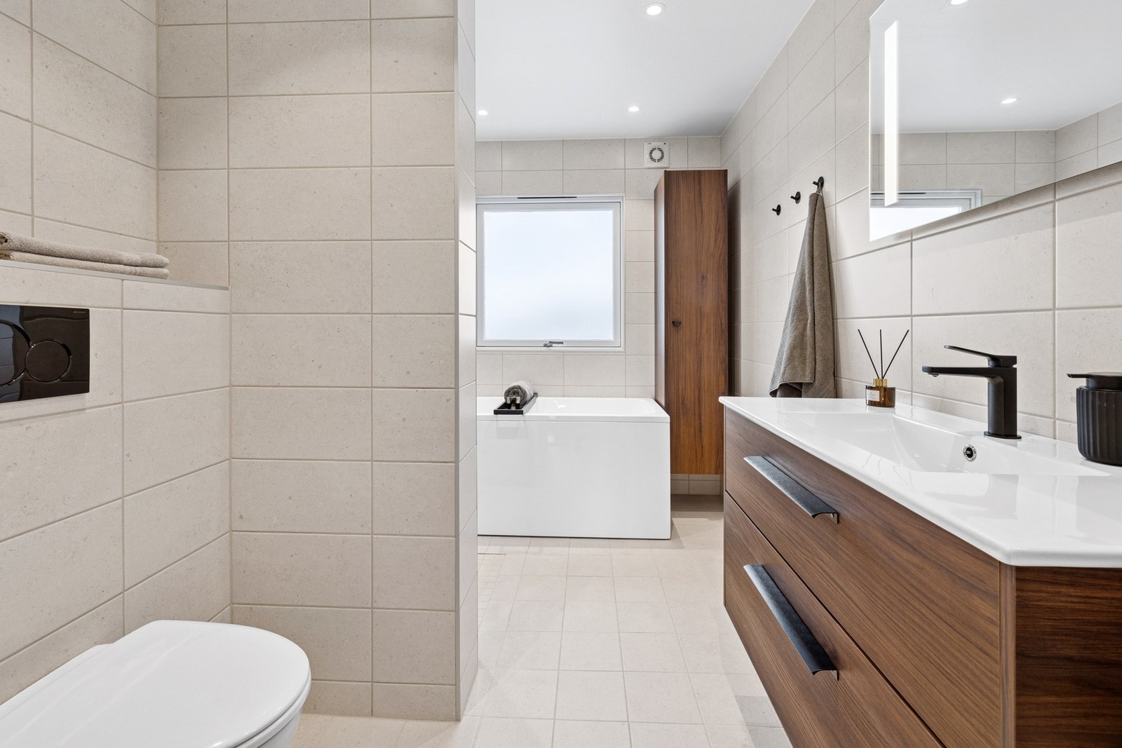 Baderommet er utstyrt med både badekar, dusjnisje med glassdører, vegghengt toalett og et flott servantskap med speil og overlys. Galleribilde