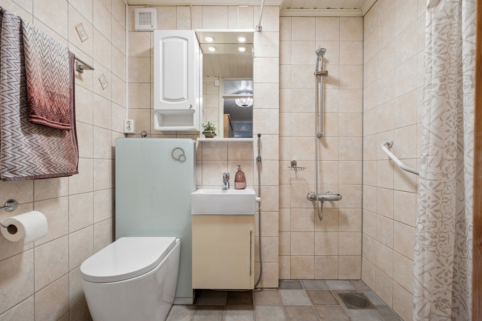 Flislagt bad utstyrt med toalett, dusjnisje og skap til oppbevaring av baderomsartikler. Toalettet vil bli byttet ut med et annet toalett til overtakelse. Galleribilde