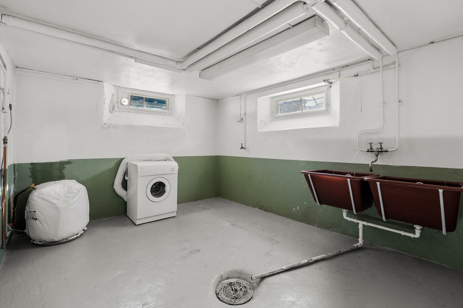 Her er det et stort vaskerom med malte murvegger og gråmalt betonggulv med sluk. Her er det potensial for et flott familiebad. Galleribilde