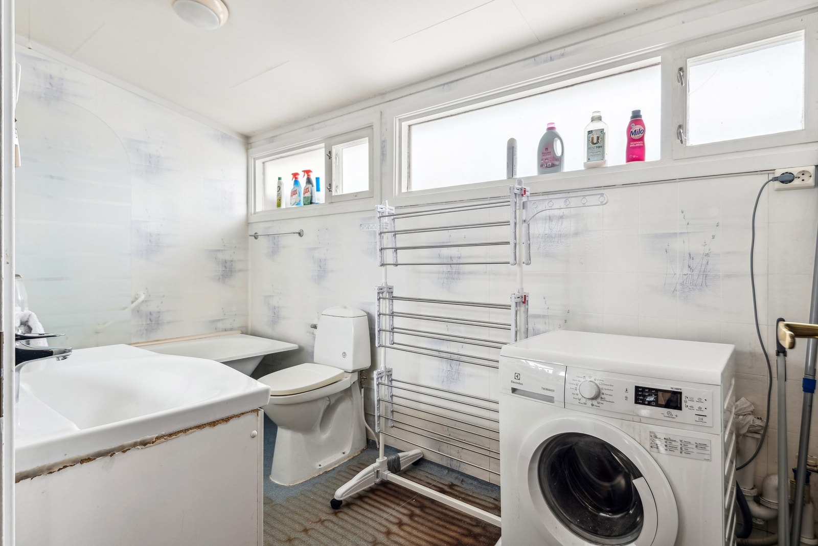 Bad/ vaskerom med behov for totalrenovering. Belegg på gulv og våtromstapet på vegger. Galleribilde