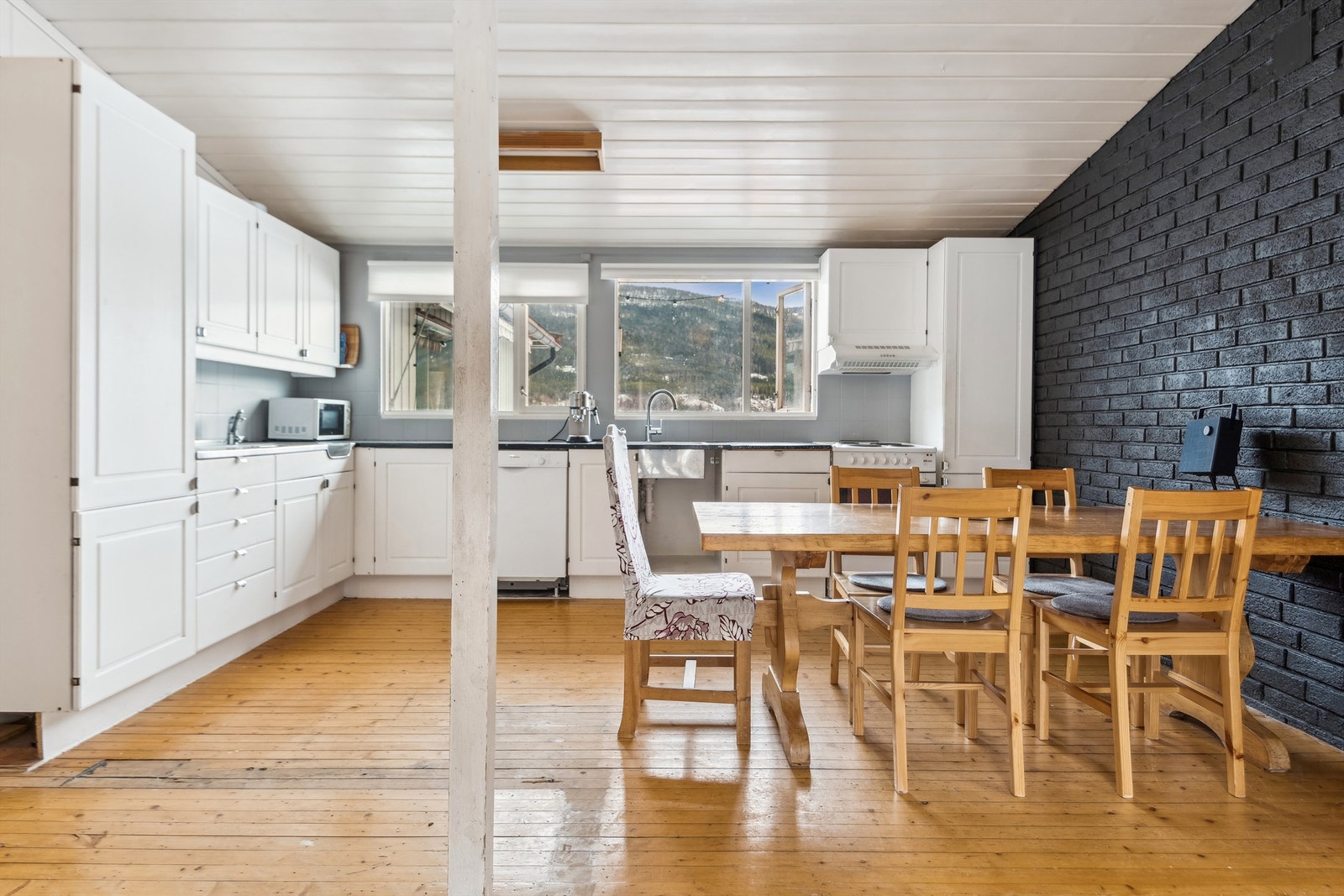 Eldre kjøkkeninnredning med profilerte fronter, laminat benkeplate, og helt beslag med kum og utslagsvask, samt fliser over benk. Galleribilde