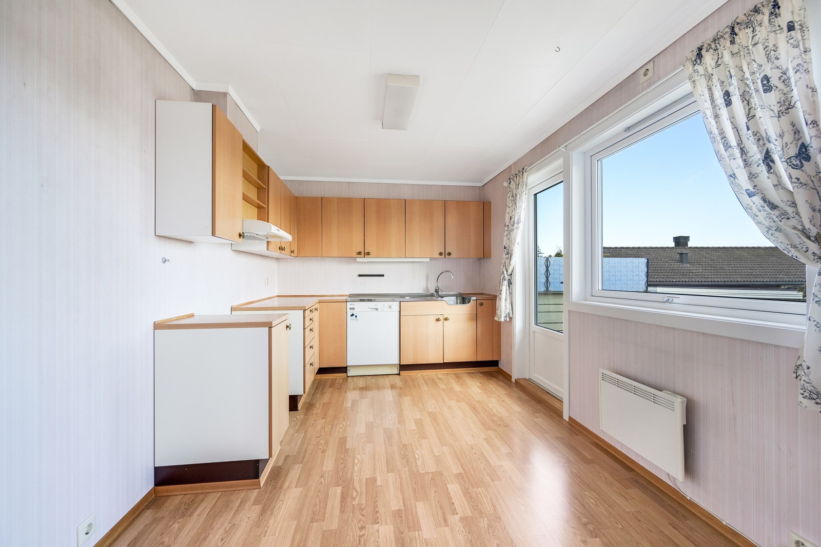 Kjøkkeninnredning med laminerte skrog, glatte fronter og laminert benkeplate med kjøkkenkum. Det er avsatt plass til frittstående kjøleskap, komfyr og oppvaskmaskin i rommet. Det er kjøkkenventilator med avtrekk ut. Galleribilde