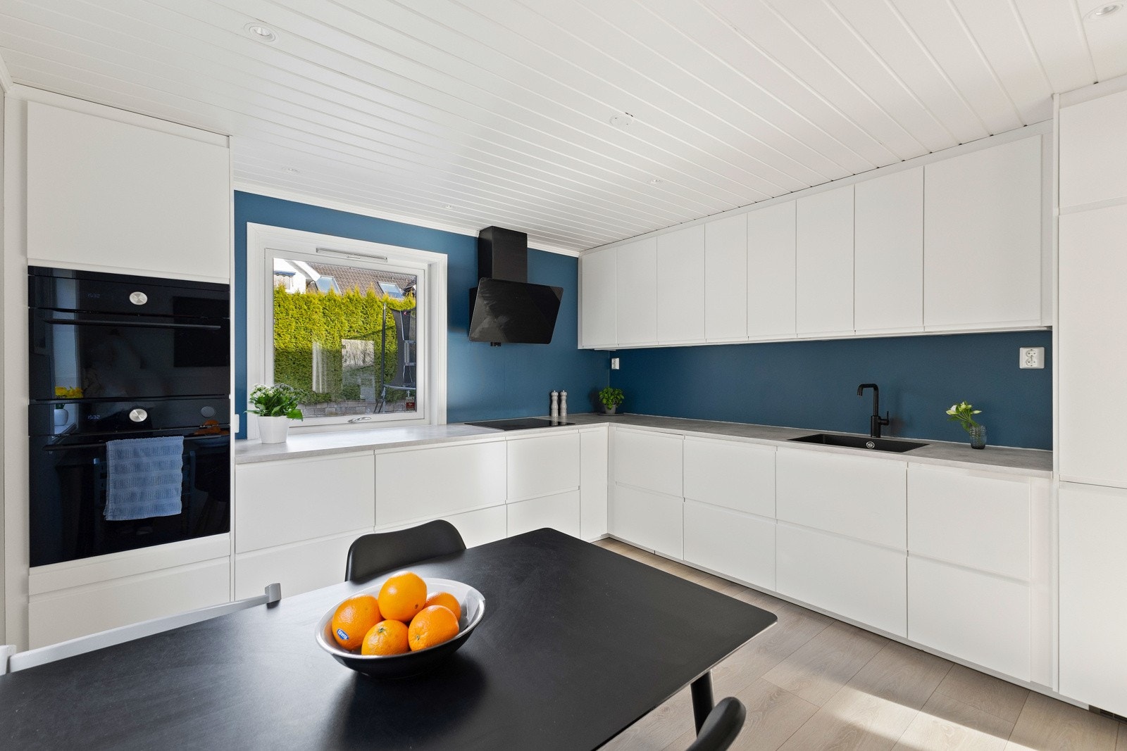 Her finner du glatte fronter, en romslig benkeplate i laminat og integrerte hvitevarer: kjøleskap, oppvaskmaskin, komfyr, induksjonstopp og mikrobølgeovn. Galleribilde