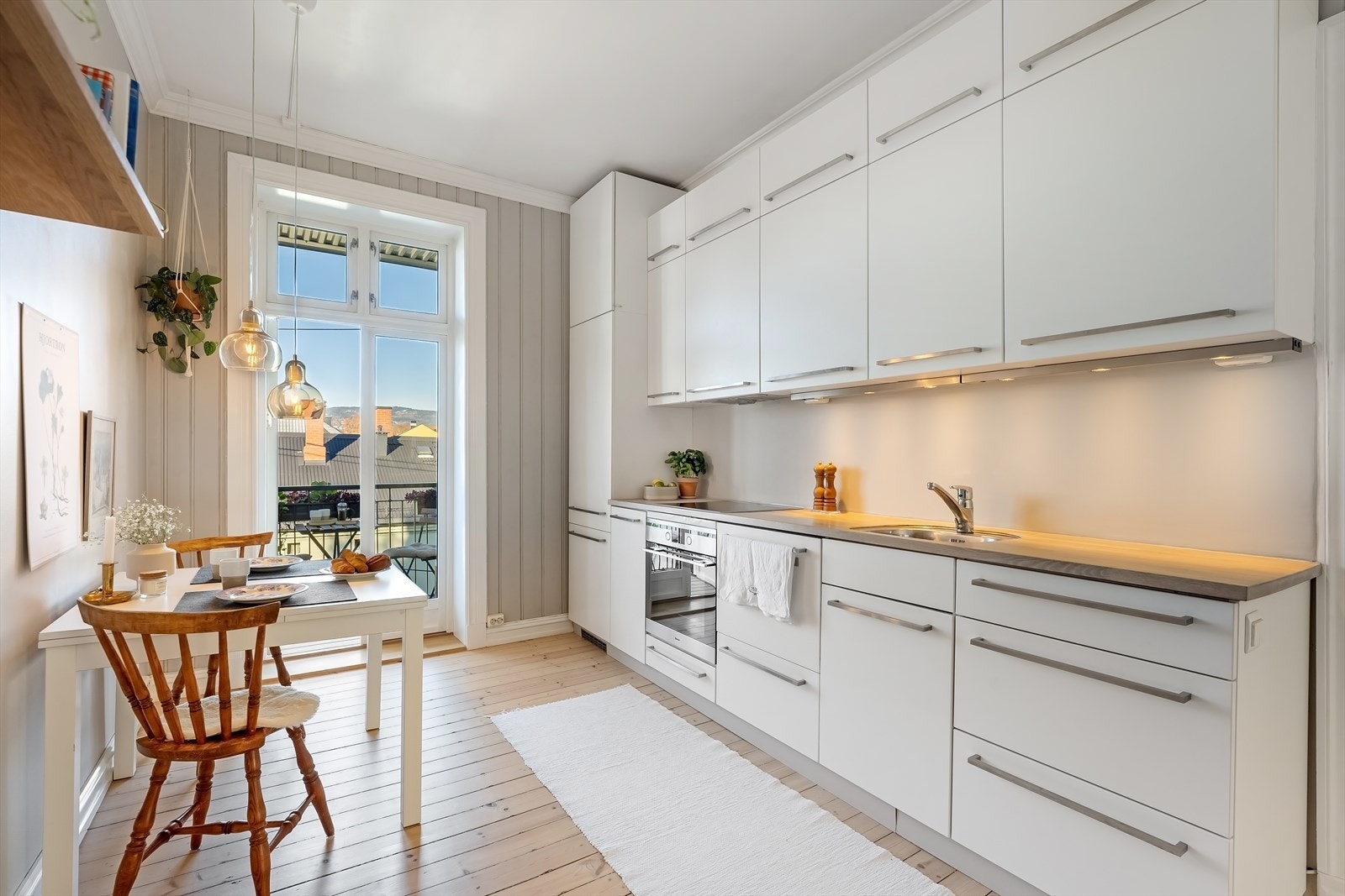 Delikat KVIK Kjøkkeninnredning fra 2008 med glatte, hvite fronter og belysning under overskap. Galleribilde