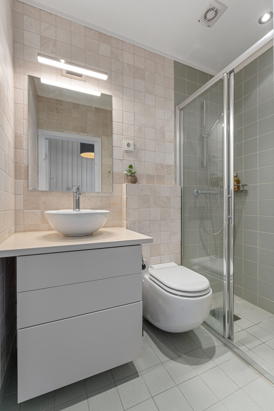 Flislagte gulv samt vegger. Baderomsinnredning bestående av benkeskap med glatte fronter og servant. Galleribilde