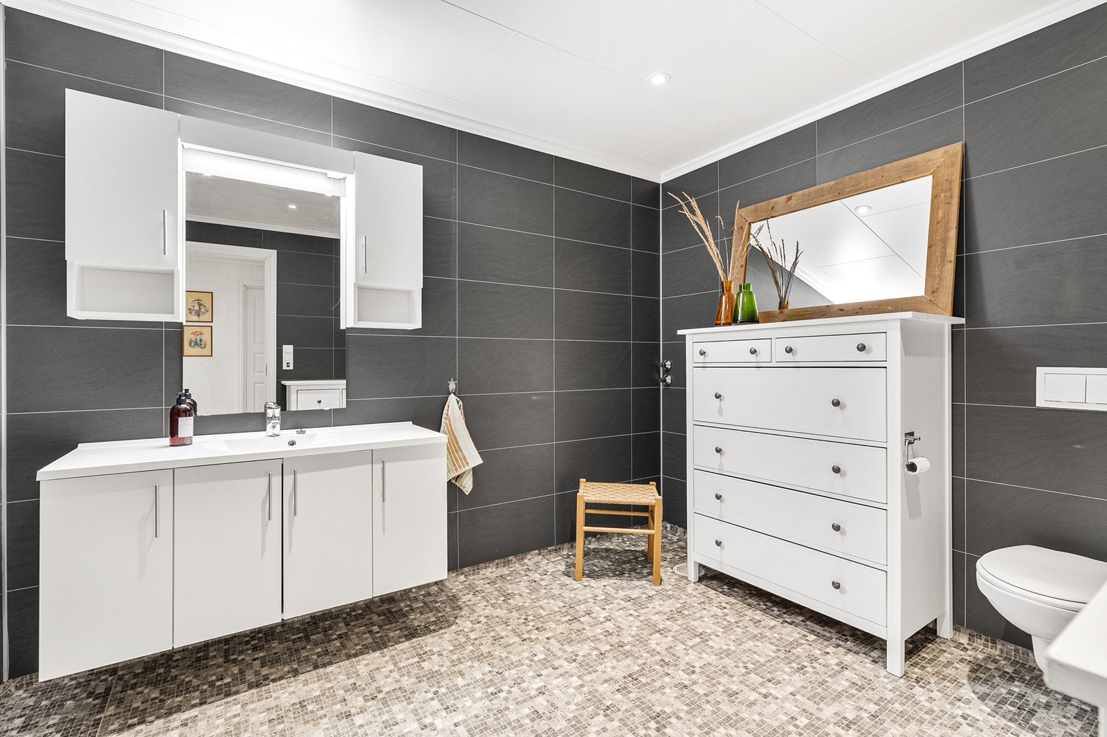 WC-rommet har vinylbelegg med varme, baderomsplater på vegger og himlingsplater. Her er det ellers innredning med nedfelt servant og veggmontert toalett. Galleribilde