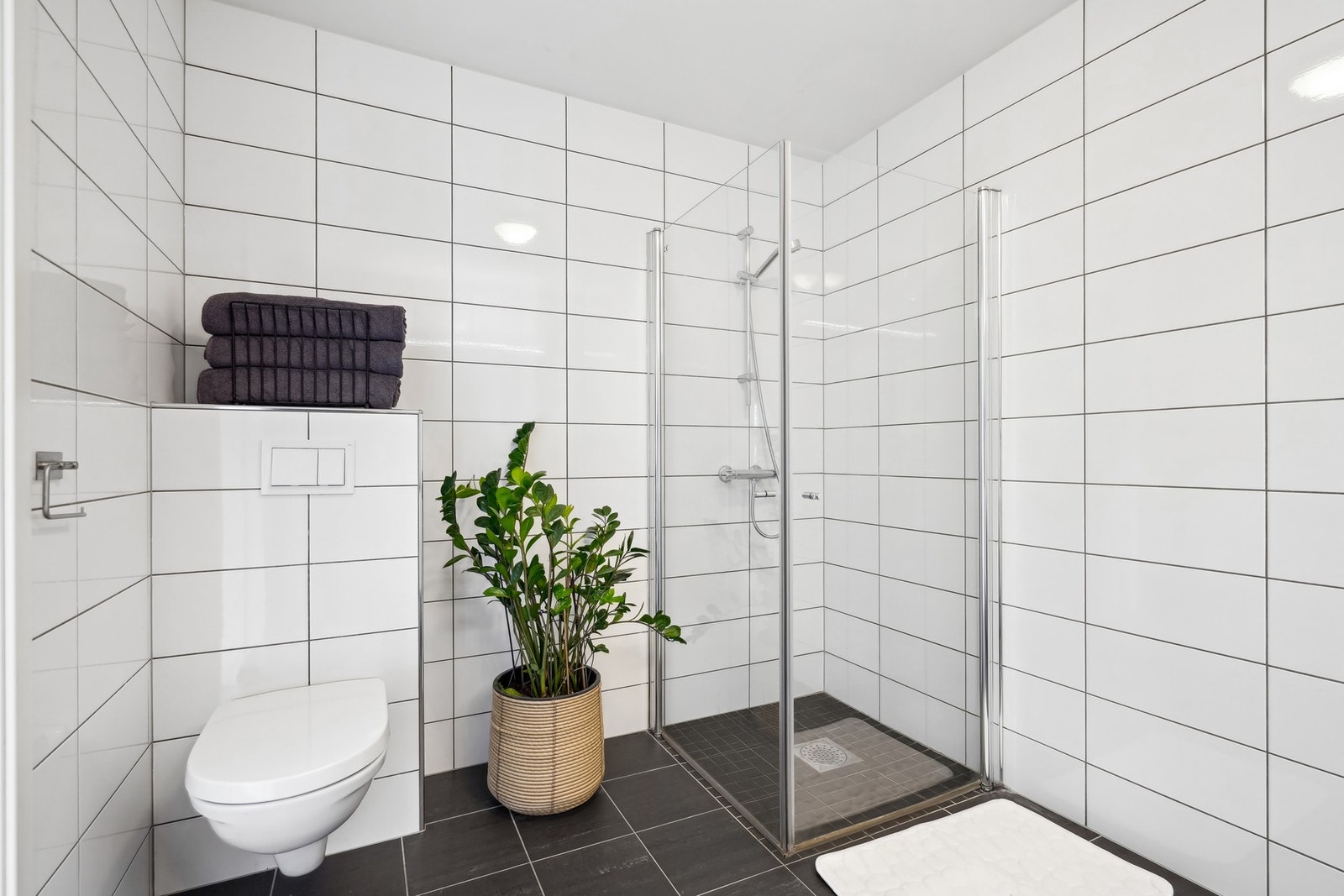 Badet er utstyrt med vegghengt toalett og dusjhjørne glassdører. Det er balansert ventilasjon på badet. Galleribilde