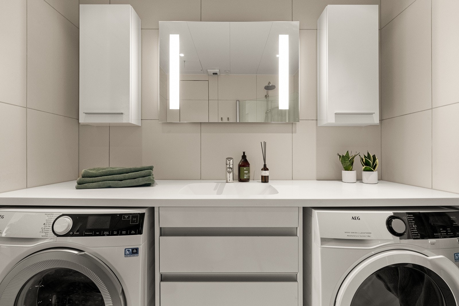 Baderommet har et lekkert og tidløst design med store beige fliser på gulv og vegger, samt downlights i himling for optimal belysning. Galleribilde