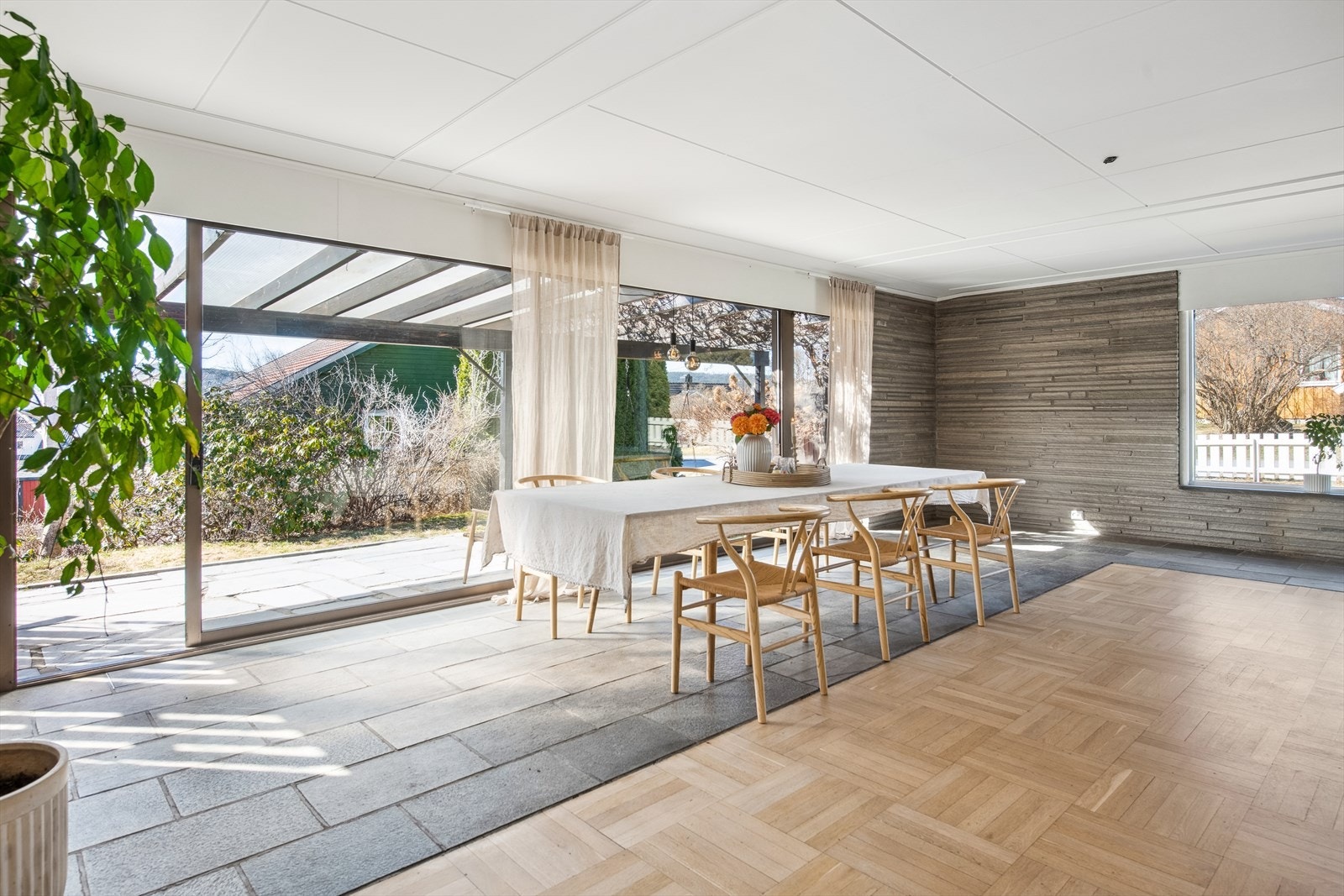 En del av stuen har bruddskifer på vegger og skifefliser på gulv. Materialer som også fortsetter ut på terrassen. Galleribilde