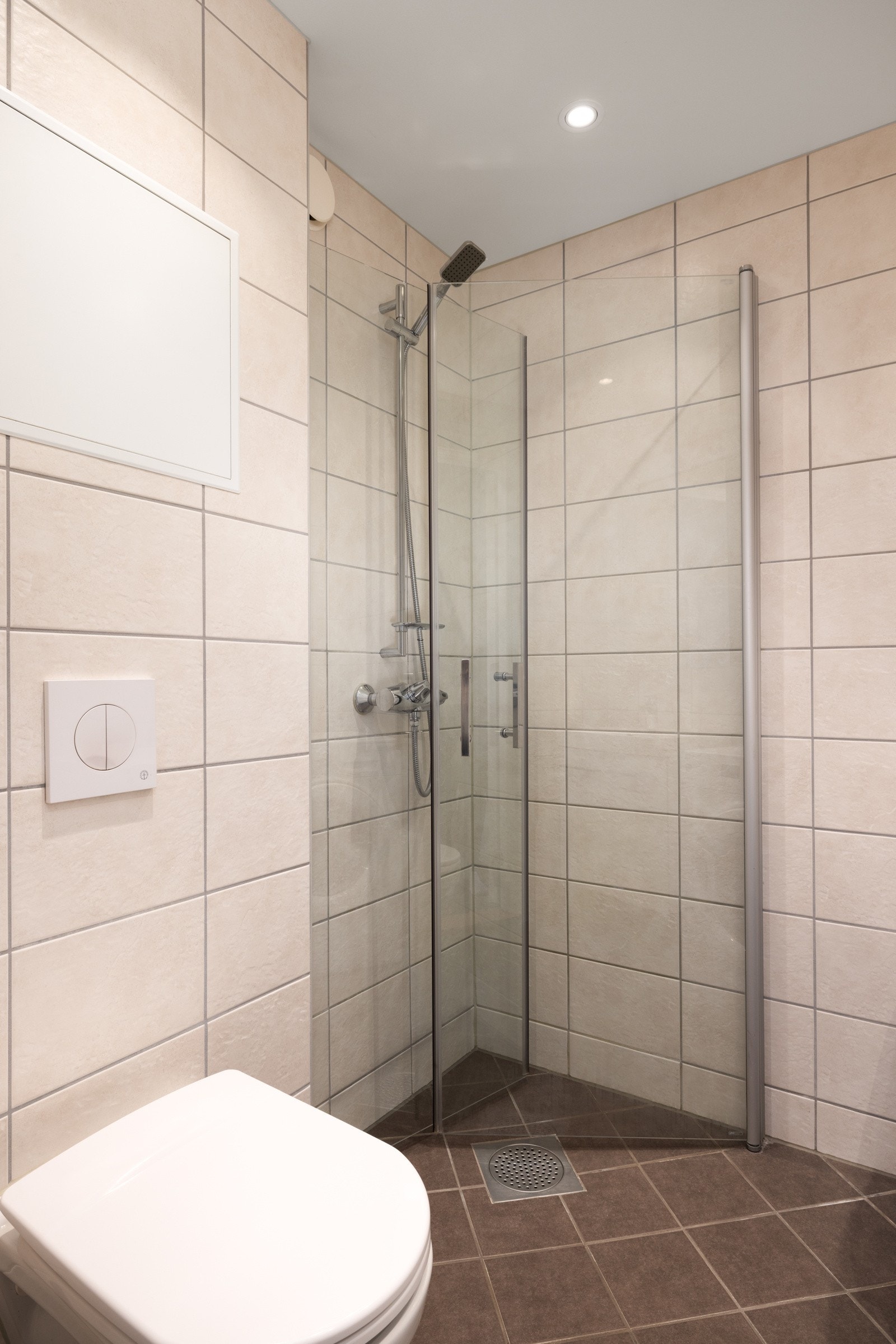 Både vegger og gulv er flislagt, og taket har malte plater med innfelte downlights. For ekstra komfort er det elektriske varmekabler i gulvet. Galleribilde