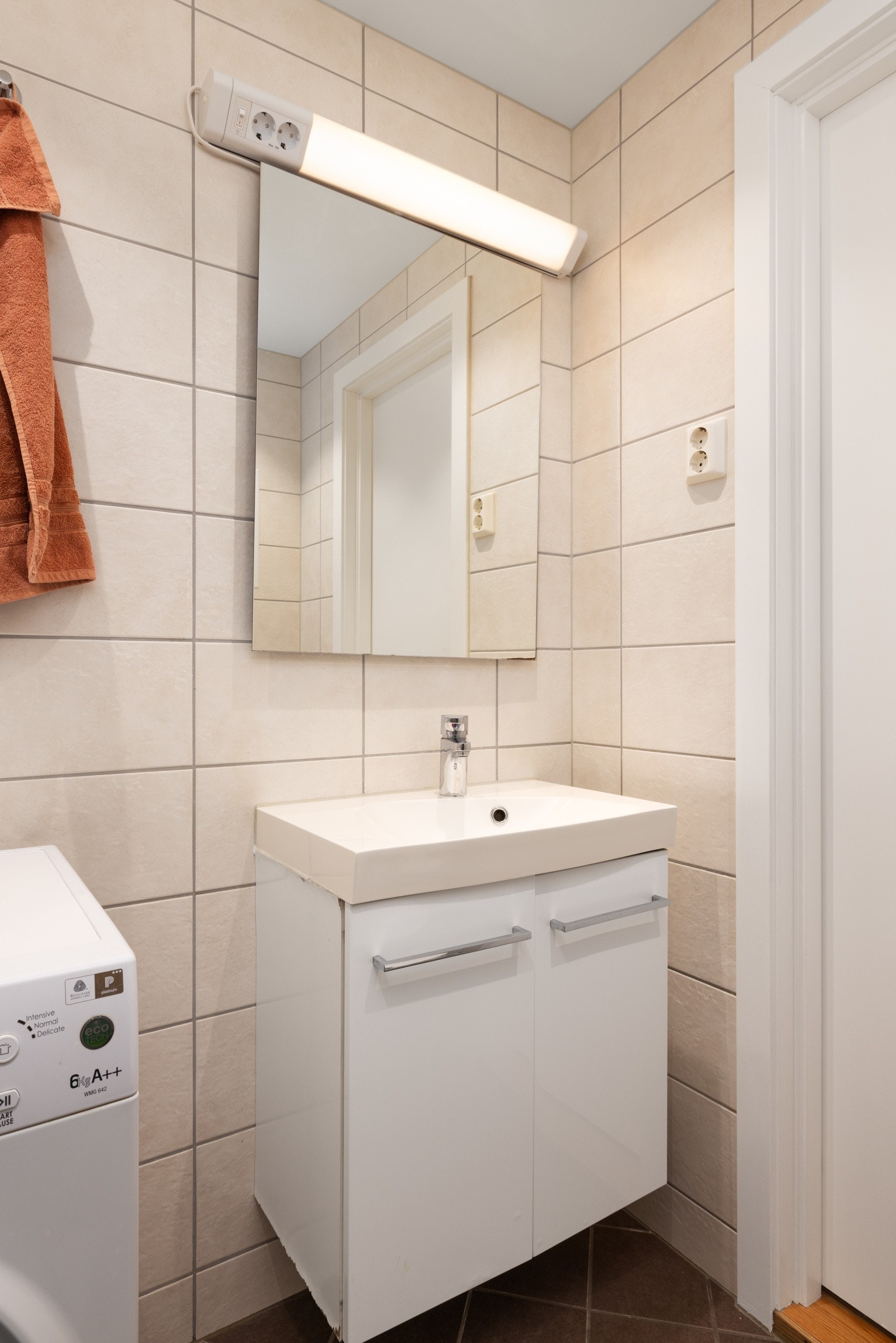 Badet er utstyrt med servant med underskap, speil, vegghengt toalett, dusjhjørne med innfellbare dører, samt praktisk opplegg for vaskemaskin. Galleribilde