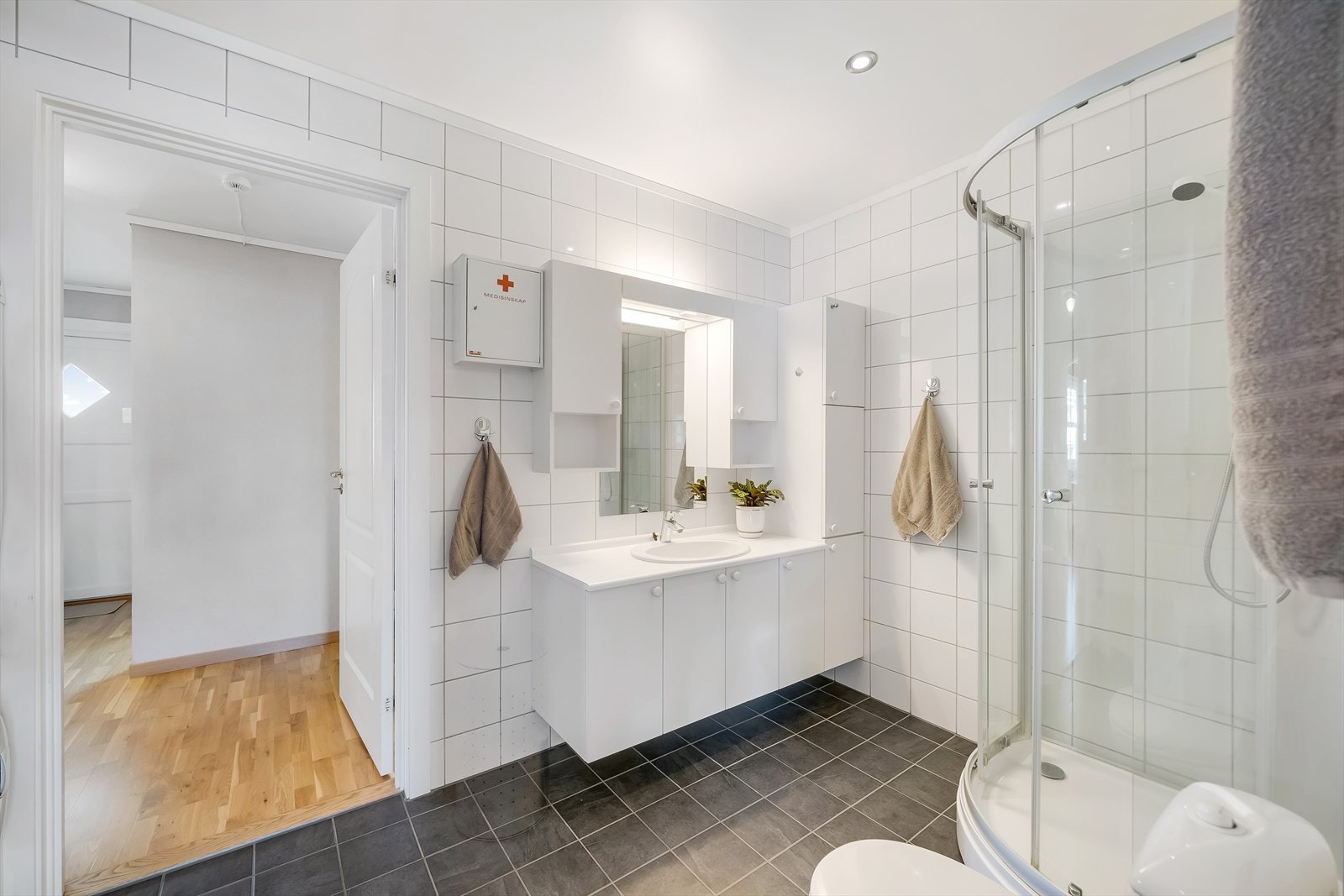 Fliselagt bad med varmekabler i gulv. Badet er innredet med baderomsinnredning, toalett og dusjkabinett. Badet har en egen baderomsavdeling. Galleribilde