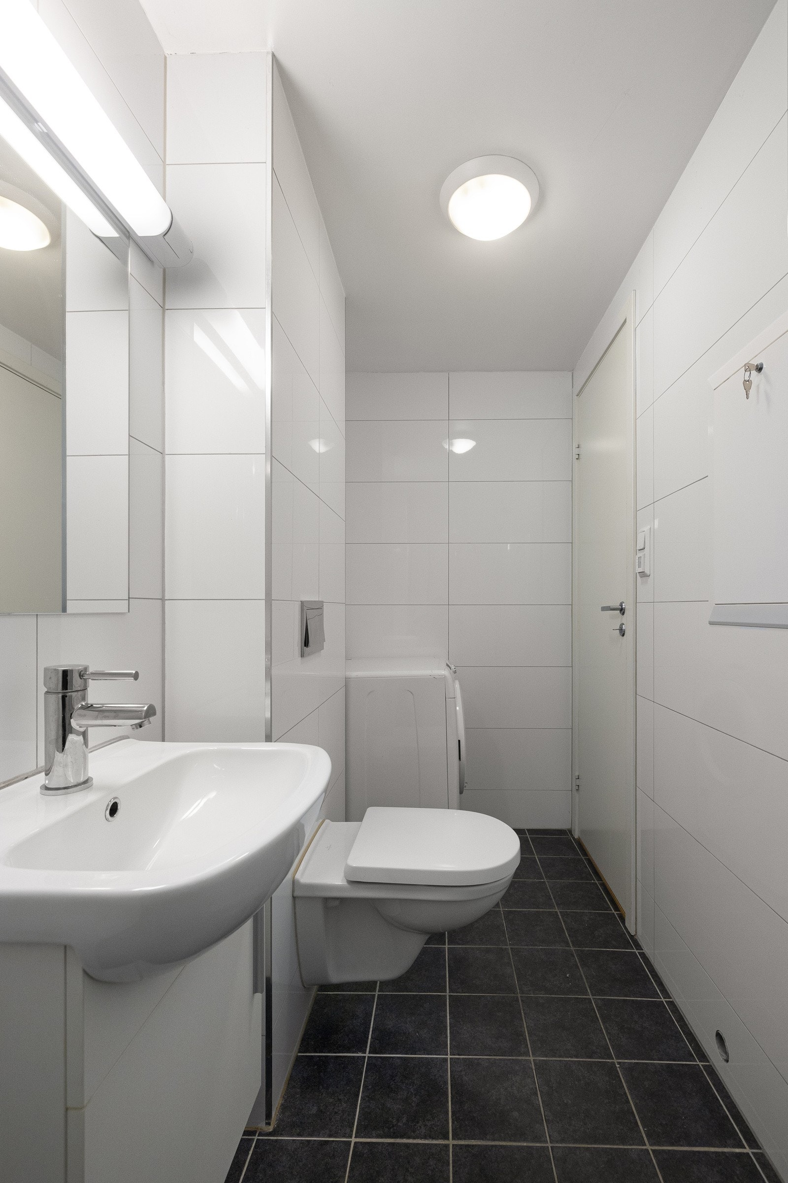 . Badet er utstyrt med opplegg for vaskemaskin, toalett og dusjhjørne med glassdører. Galleribilde