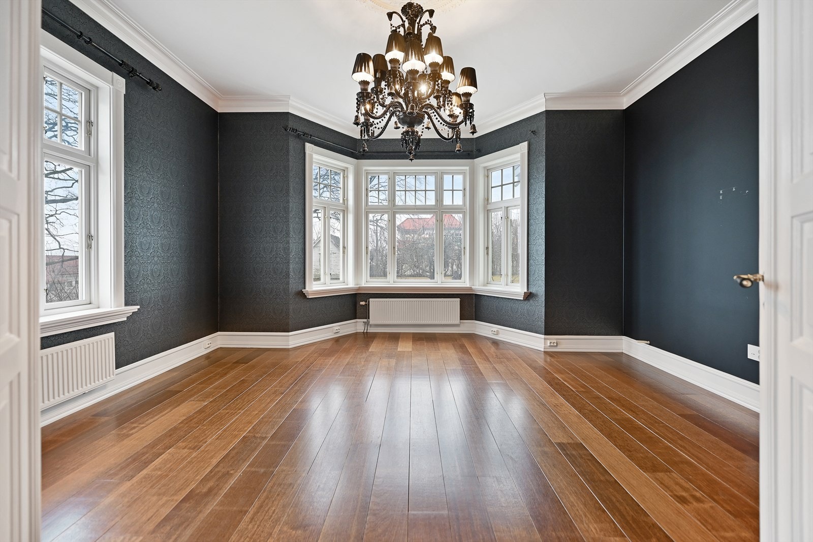 Fra TV-stuen er det hyggelig utsyn mot hagen og rommet har mørk blå mønstertapet. Galleribilde