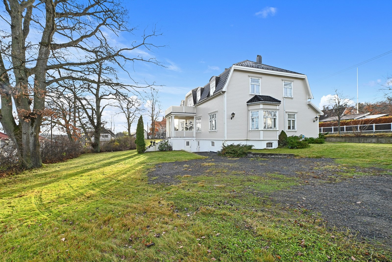 Parkering gjøres på gruset gårdsplass. Det er montert ladepunkt for elbil på hushjørnet. Galleribilde