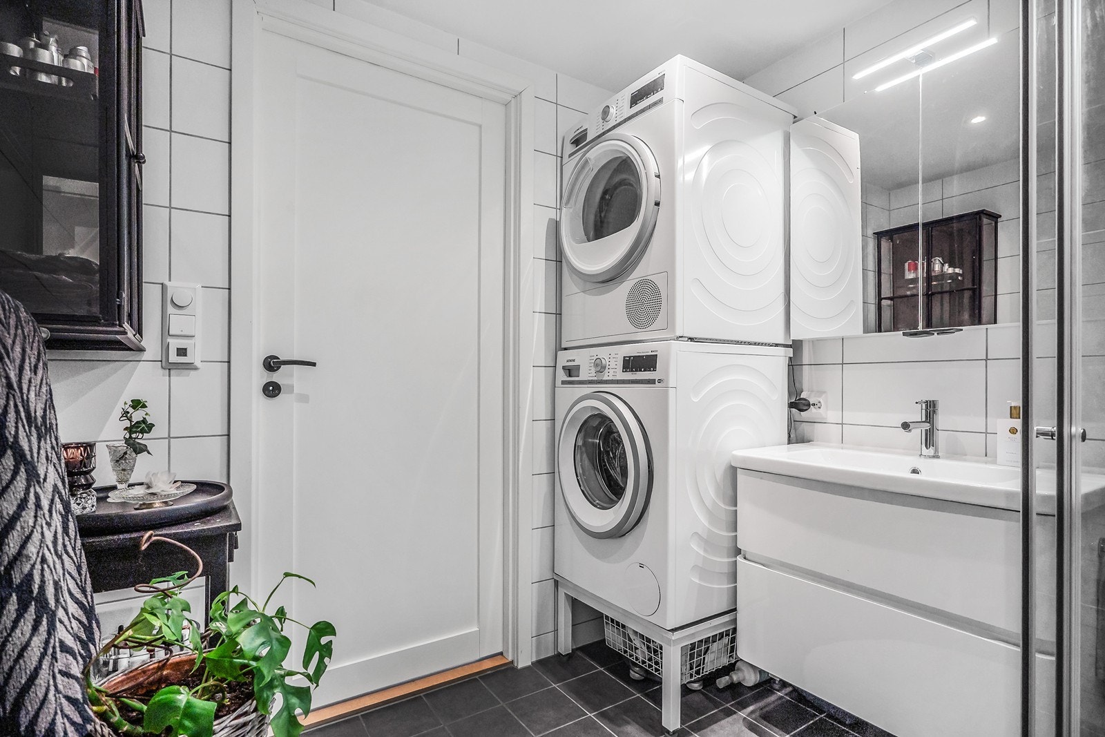 Videre er det skuffeinnredning med bredt servantskap, speilskap og opplegg for vaskemaskin og tørketrommel. Galleribilde
