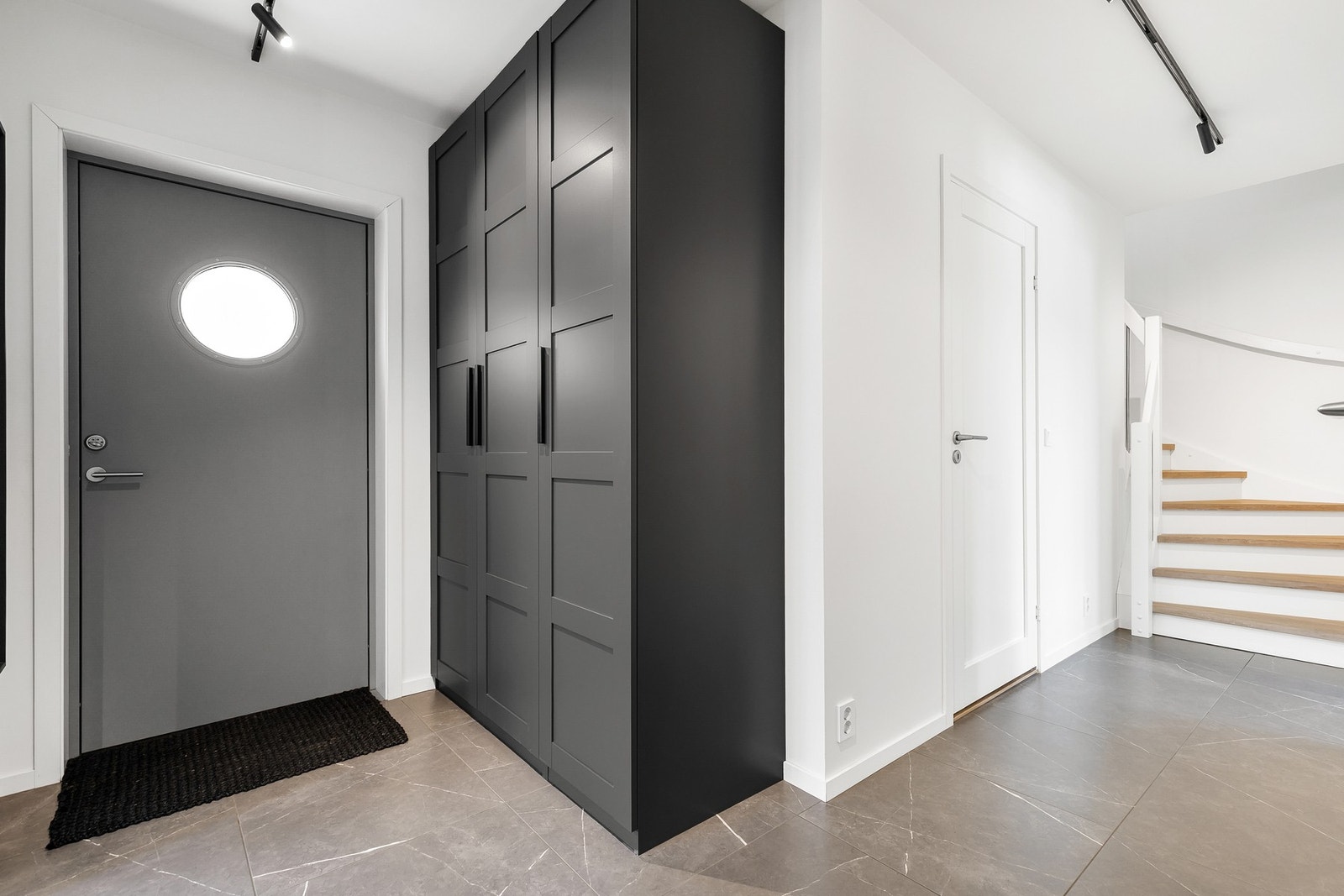 Romslig entré med fliser på gulv og god plass til garderobeskap for oppbevaring av yttertøy og sko Galleribilde