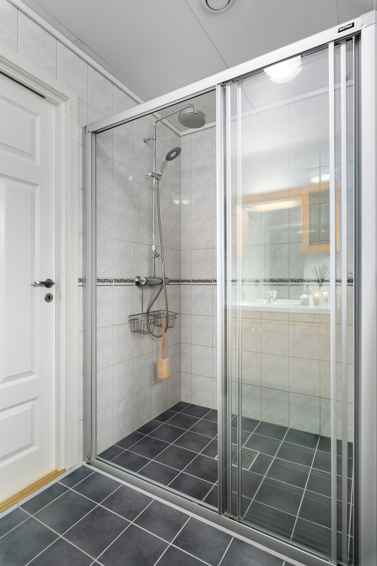 Boligen har to bad, og dette er helfliset hovedbad som har romslig dusjnisje med skyvedører Galleribilde