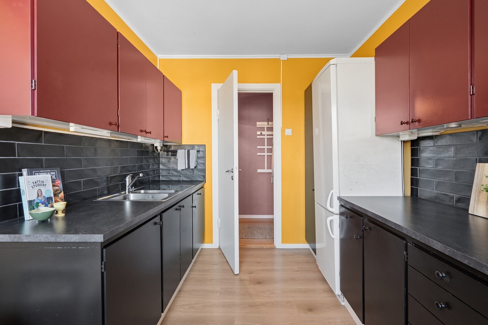 Kjøkkeninnredningen er pent og moderne utført med sorte og røde, glatte fronter, og sort laminert benkeplate. Galleribilde