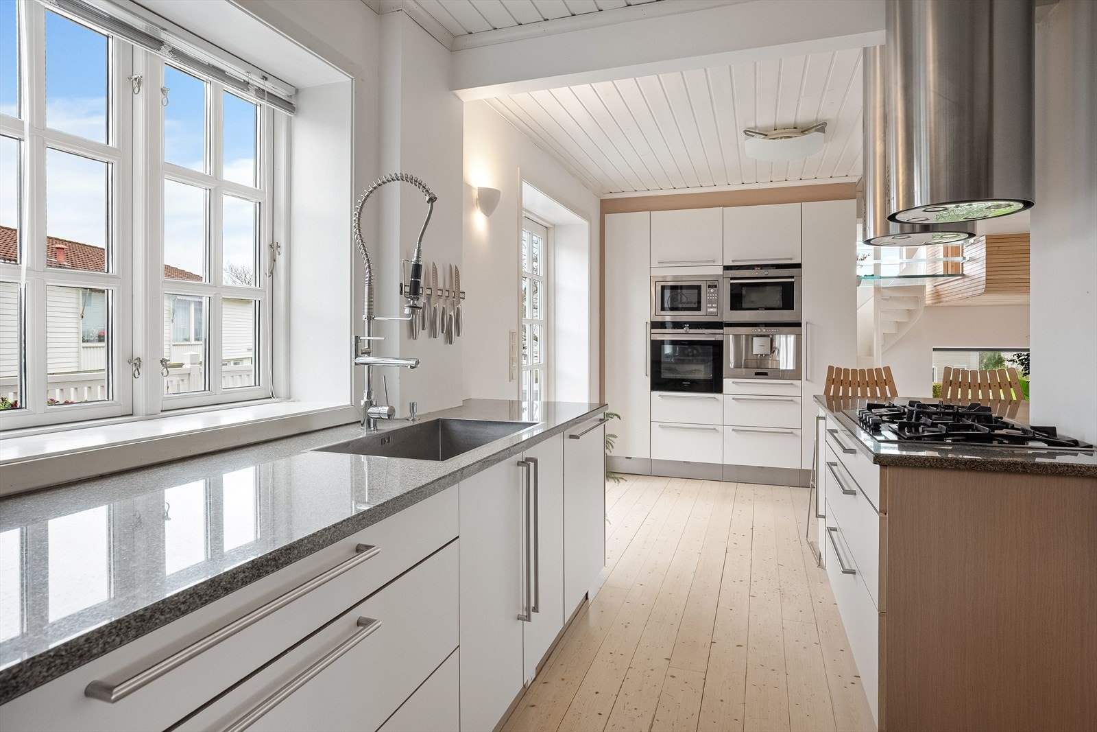 Lyst og moderne kjøkken med integrerte hvitevarer, romslig benkeplass og store vinduer som slipper inn rikelig med naturlig lys. Galleribilde