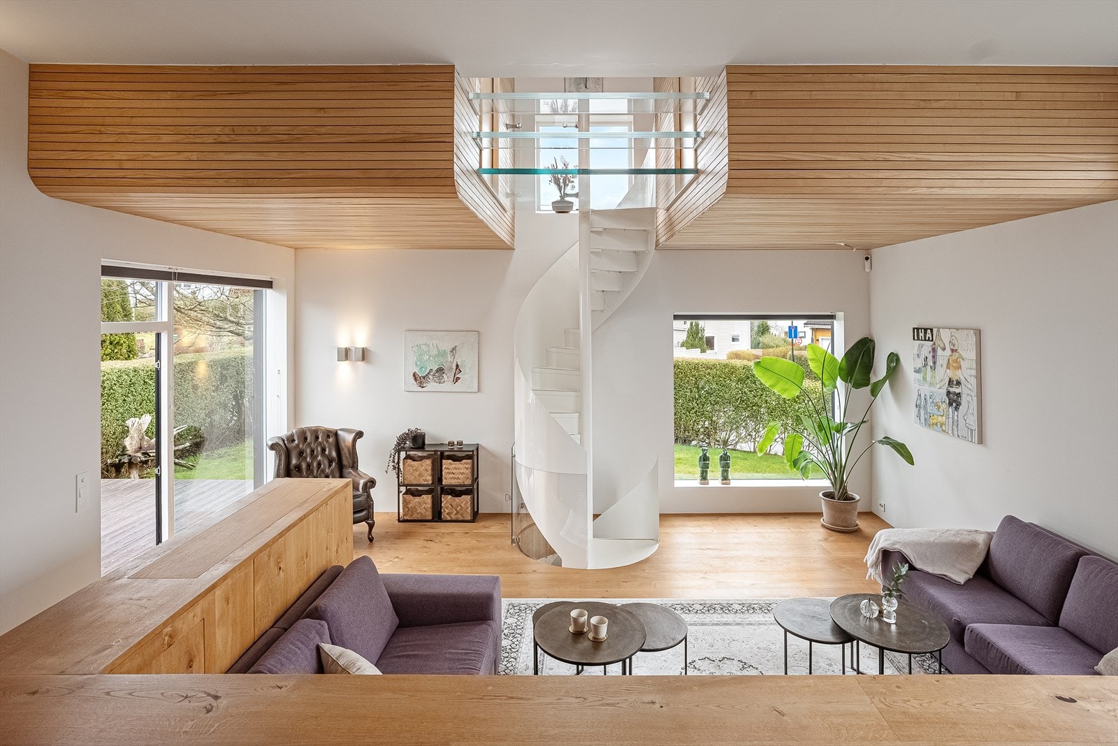 Moderne stue med elegant, spiralformet trapp og store vinduer som gir rikelig med naturlig lysinnslipp og utsikt til hagen. Galleribilde