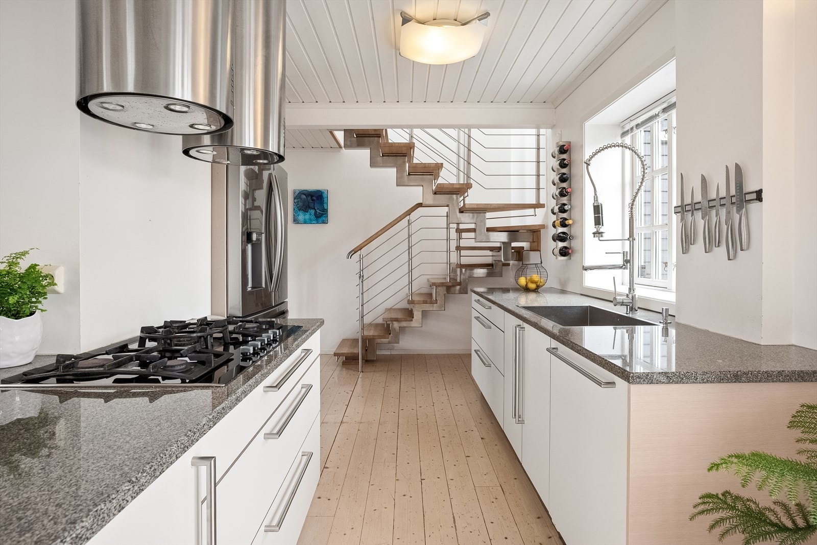 Moderne kjøkken med lyse overflater og stilfull design, perfekt for matlaging og sosiale sammenkomster. Åpen løsning med elegante detaljer. Galleribilde