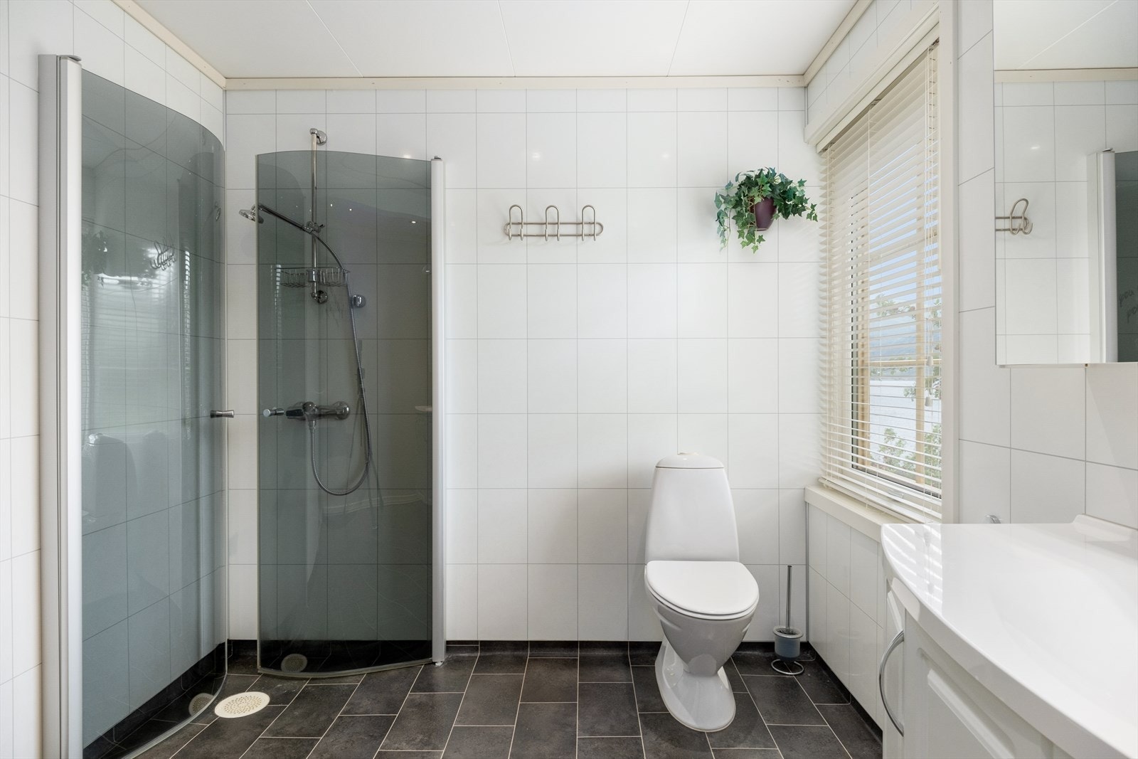 Badet er innreia med toalett, nedfelt servant med underskåp, overskåp med spegel og lys, dusjhjørne med innfellbare glasveggar. Galleribilde