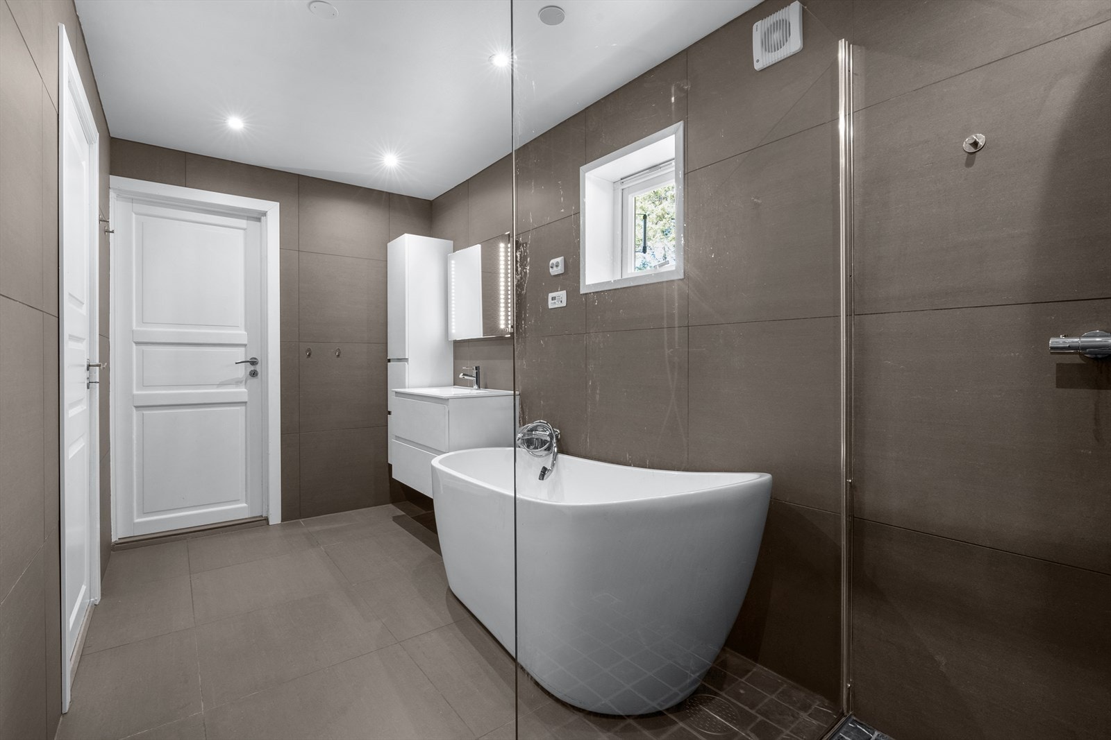 Badet er utstyrt med badekar, downlights i himgling og dusjhjørne med regn- og hånddusj. Galleribilde
