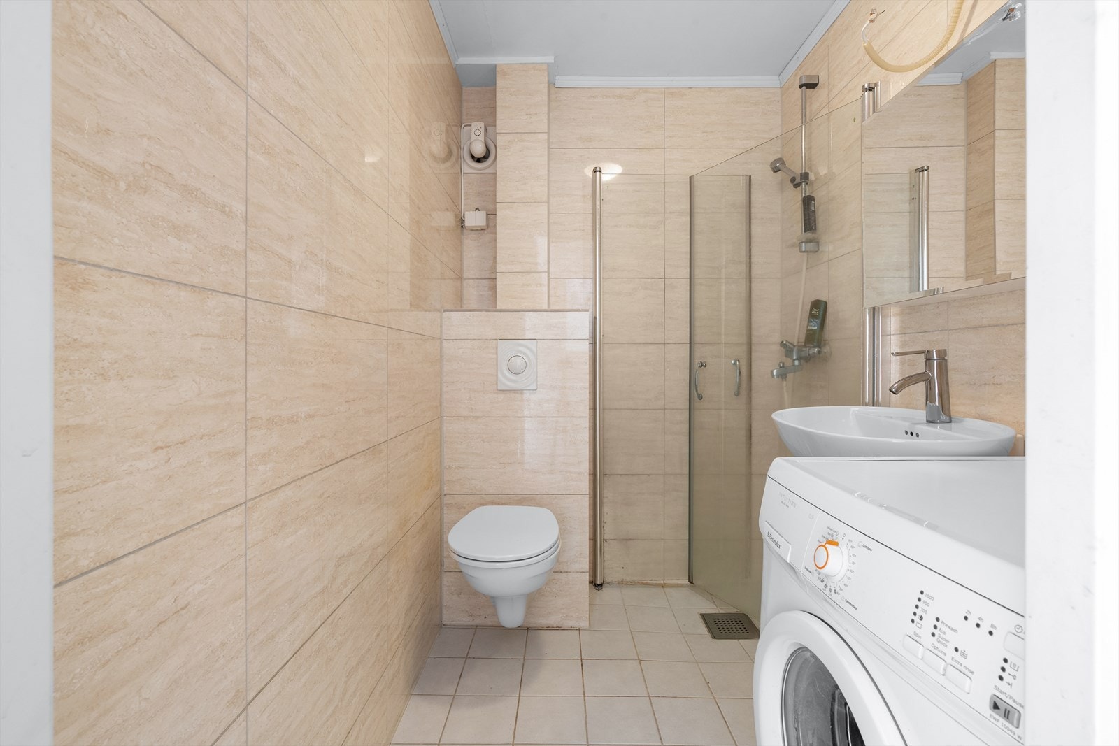 Flislagt baderom med vannbåren varme. Badet er utstyrt med dusjhjørne, vegghengt toalett, servant og opplegg for vaskemaskin. Galleribilde