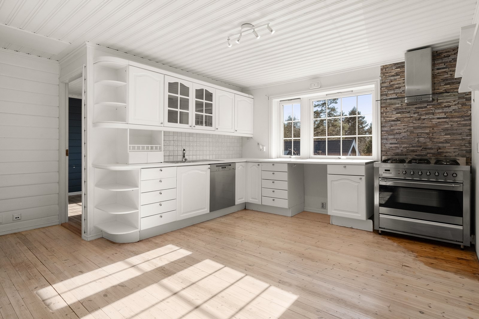 Kjøkkeninnredningen har hvitmalte, profilerte fronter og det er laminate benkeplater. Kjøkkenet er utstyrt med integrert komfyr med keramisk koketopp, innebygd vifte og opplegg til oppvaskmaskin. Galleribilde