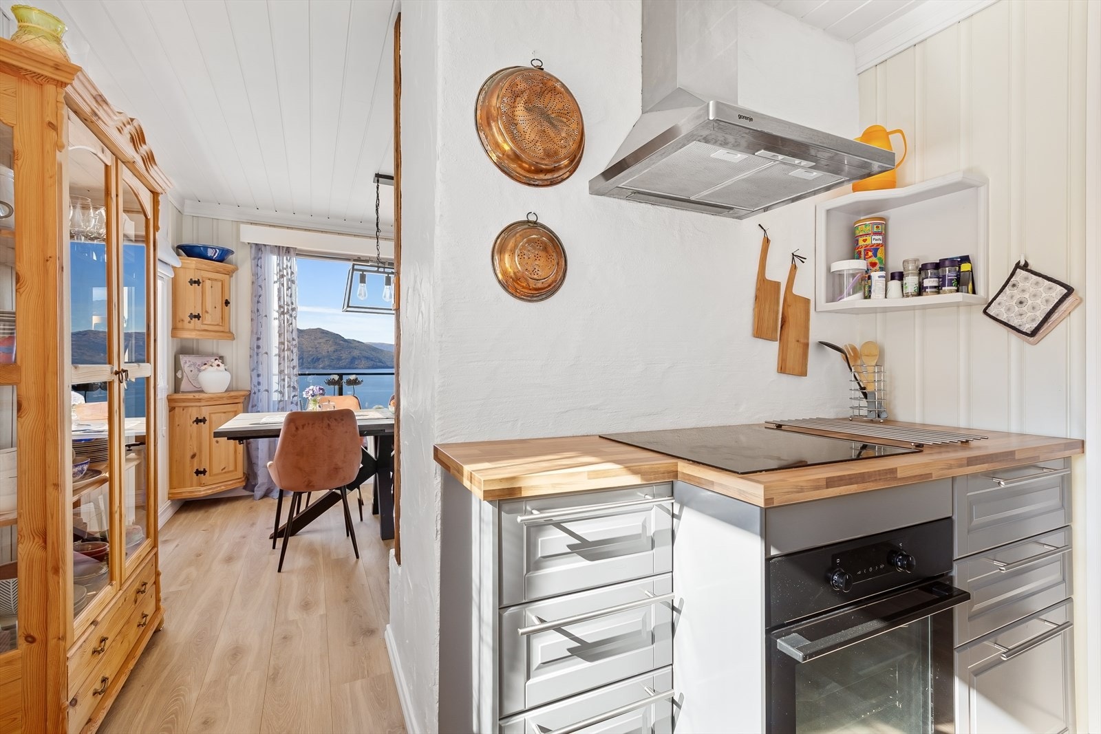 Kjøkkenet ligger i åpen løsning mot stuen og er utstyrt med gråblå innredning, trefarget benkeplate og moderne hvitevarer Galleribilde