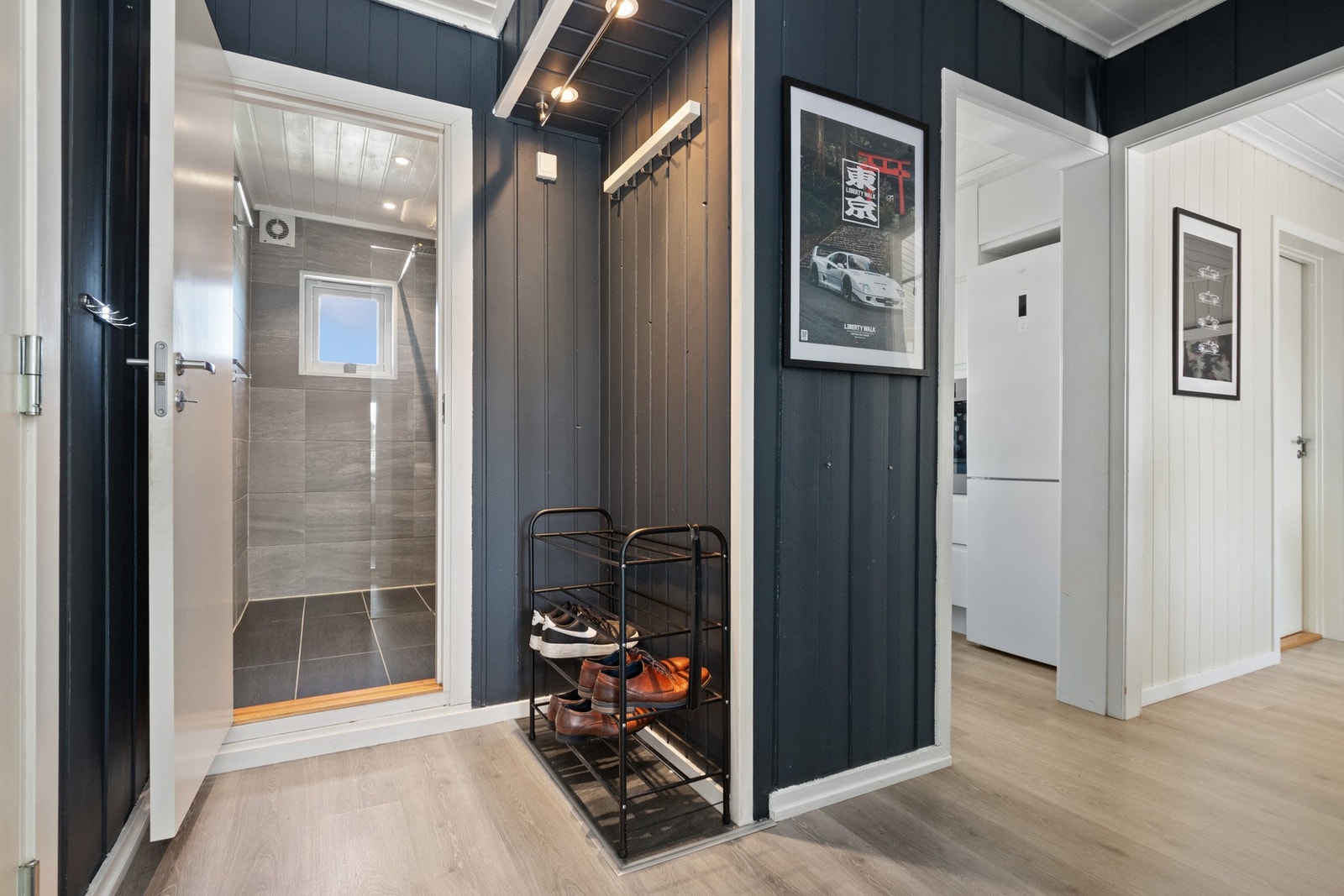 Leiligheten har en pen entré med mørkeblå panel på veggene og lyst, enstavs laminat på gulvet. Galleribilde