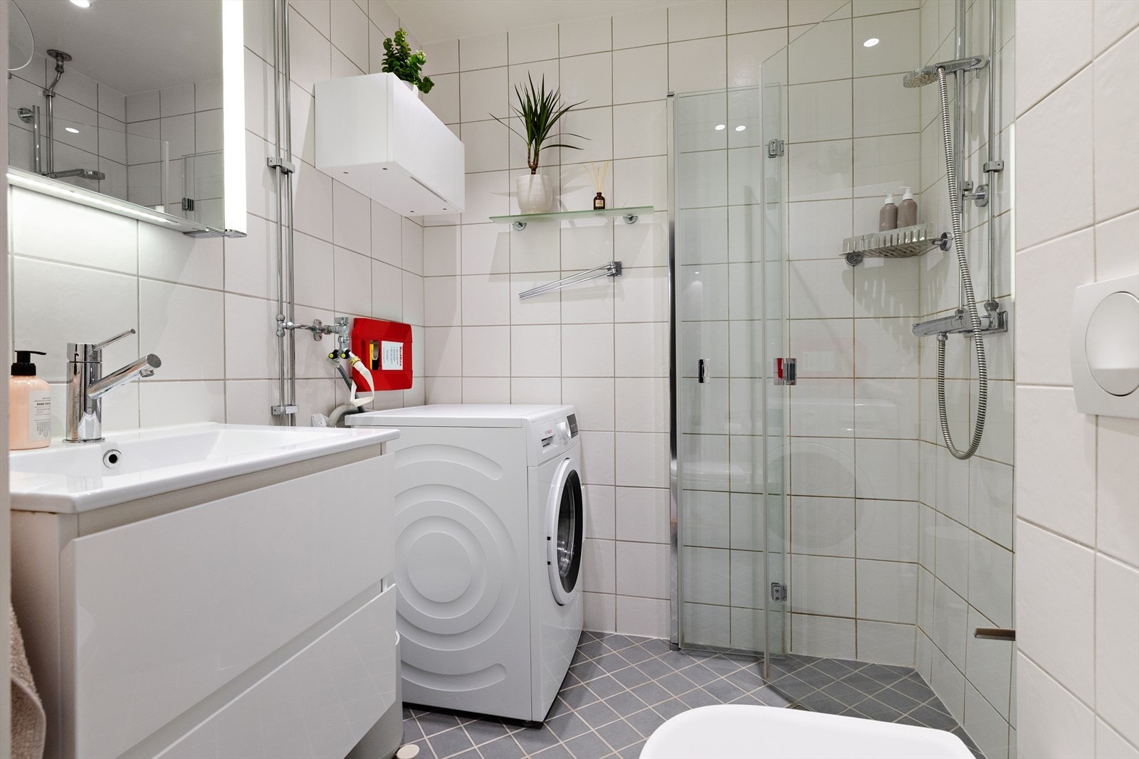 Tidløst flislagt baderom med gulvvarme og opplegg til vaskemaskin. Galleribilde