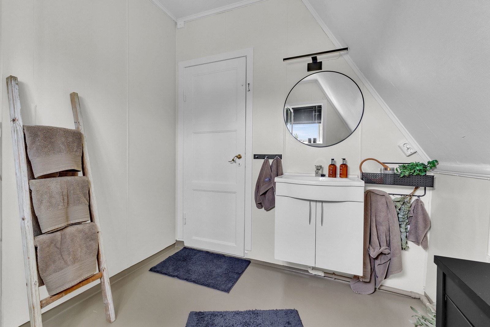 Baderomsinnredningen har hvite, glatte fronter og består av en heldekkende servant på en skapseksjon, et stort speil og god belysning. Galleribilde