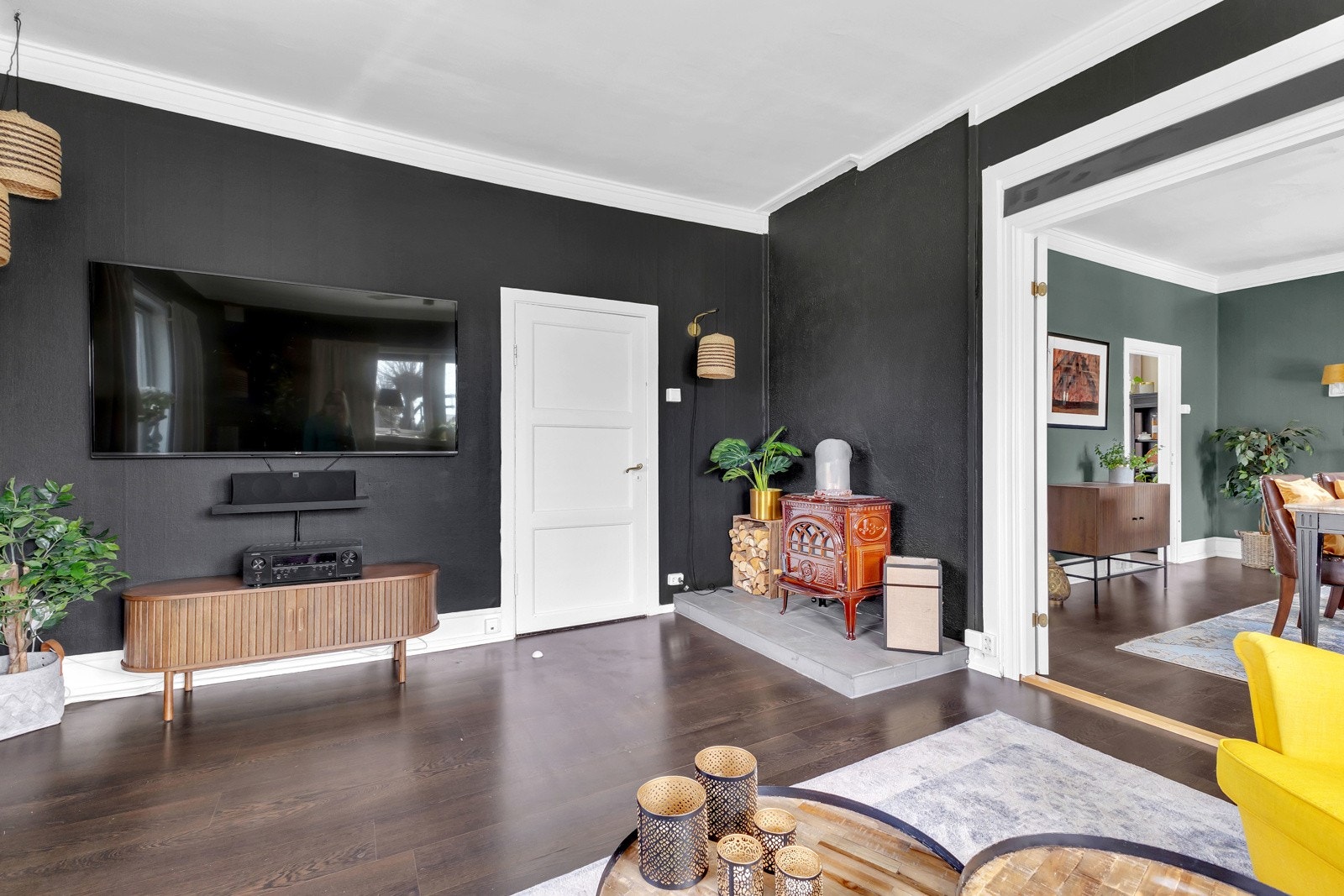Stuen har sortmalte vegger mot mørkt laminatgulv, og i et hjørne er det en god peisovn i støpejern. Galleribilde