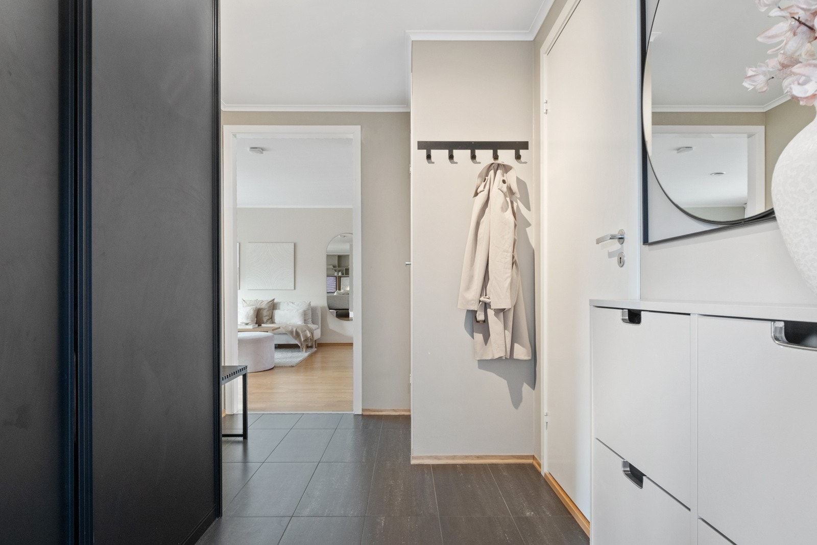 Langs den ene veggen er det bygd inn en stor skyvedørsgarderobe med sorte fronter, og ved motsatt vegg er det skoskap. Galleribilde