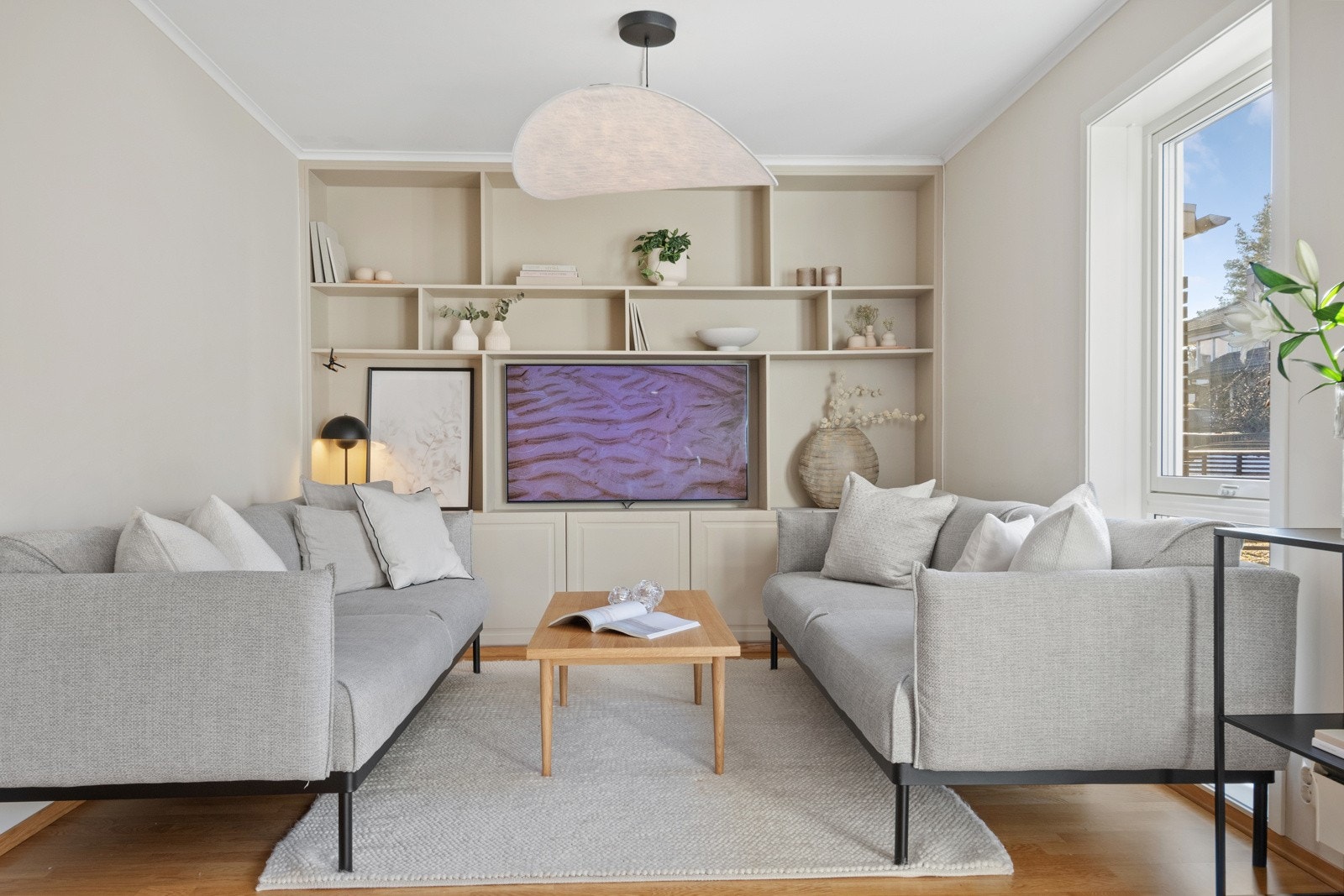 Langs hele den innerste veggen i rommet er det en plassbygd reol med bokhyller, skapdører nederst og avsatt plass til flatskjerm. Galleribilde