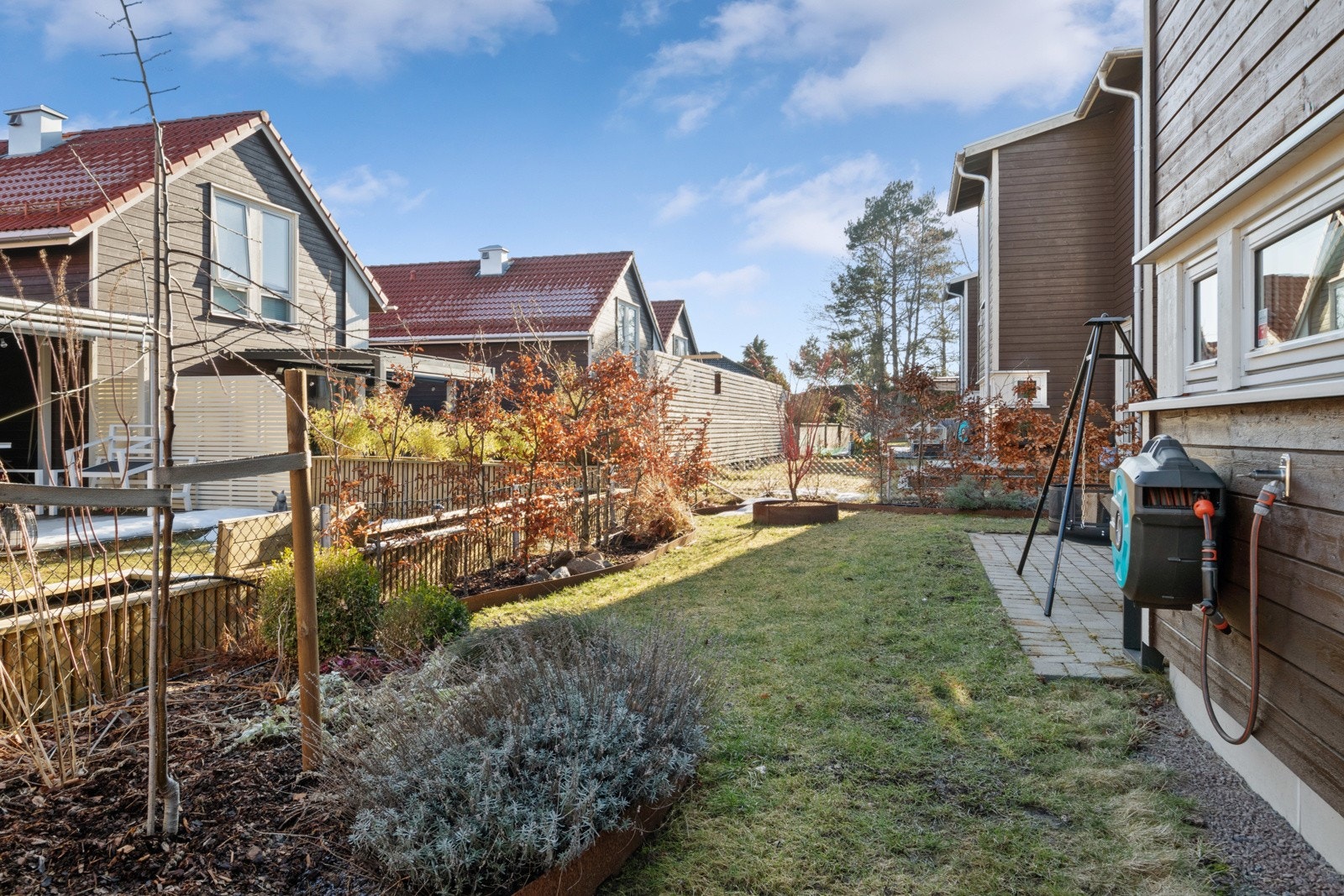 Tomten er lettstelt og pent opparbeidet med asfaltert gårdsplass og carport langs siden, plenareal mot øst og en skjermet, solrik hage mot vest. Galleribilde